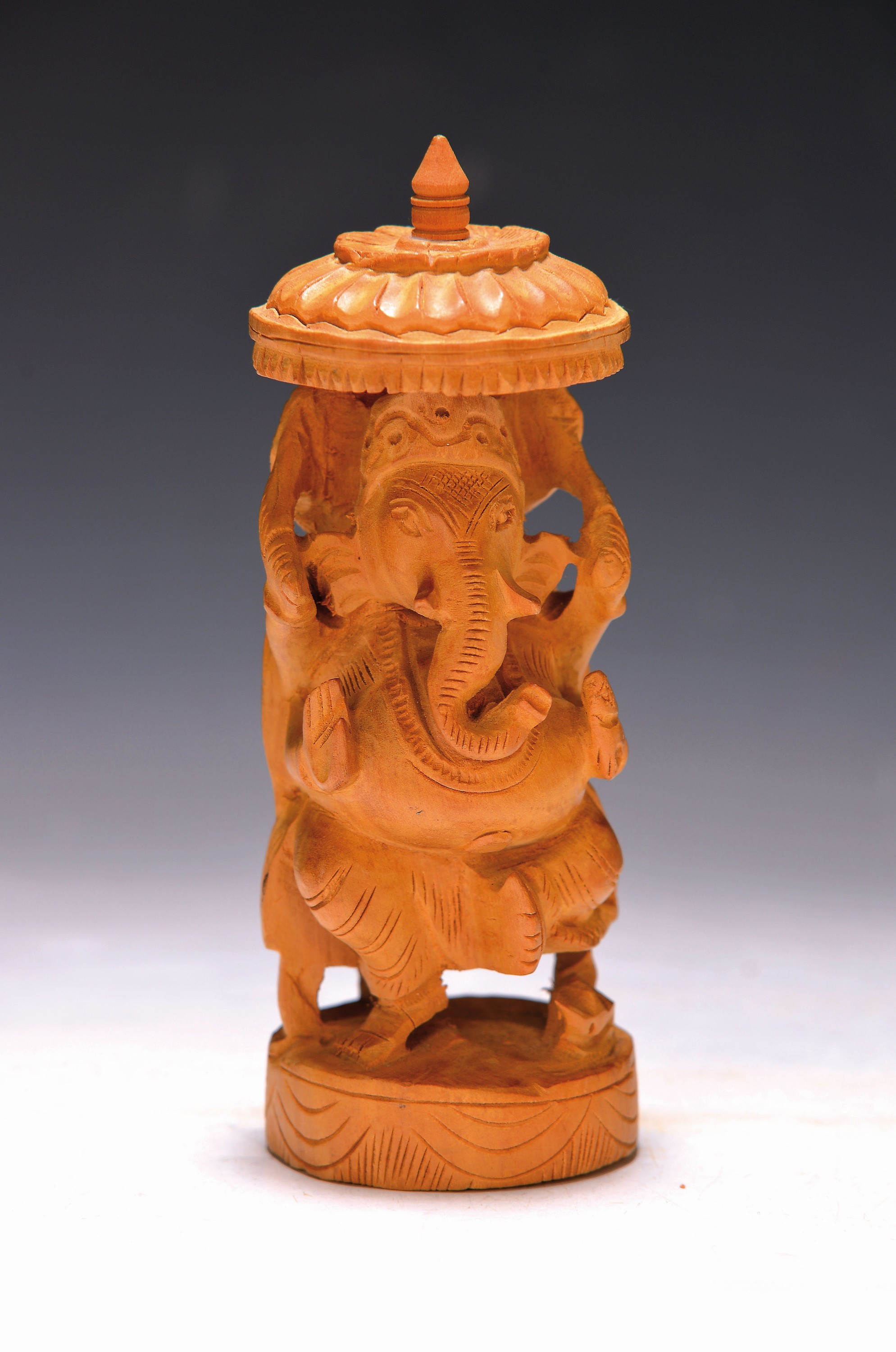 Skulptur des Gottes Ganesha, Indien, um 1920/30, Sandelholz fein geschnitzt, in Elefantengestalt sitzend unter einem Schirm, H. ca. 14cm