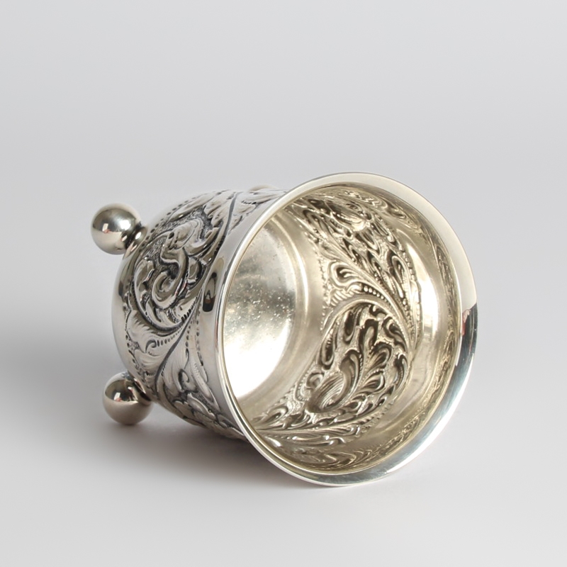 Detail b: Silberbecher, 20.Jh., 830er-Silber, barockisierender Dekor mit Blüten und Ranken, drei Kugelfüße, ungedeutete Vogelmarke, ca. 149 g, H. 9 cm