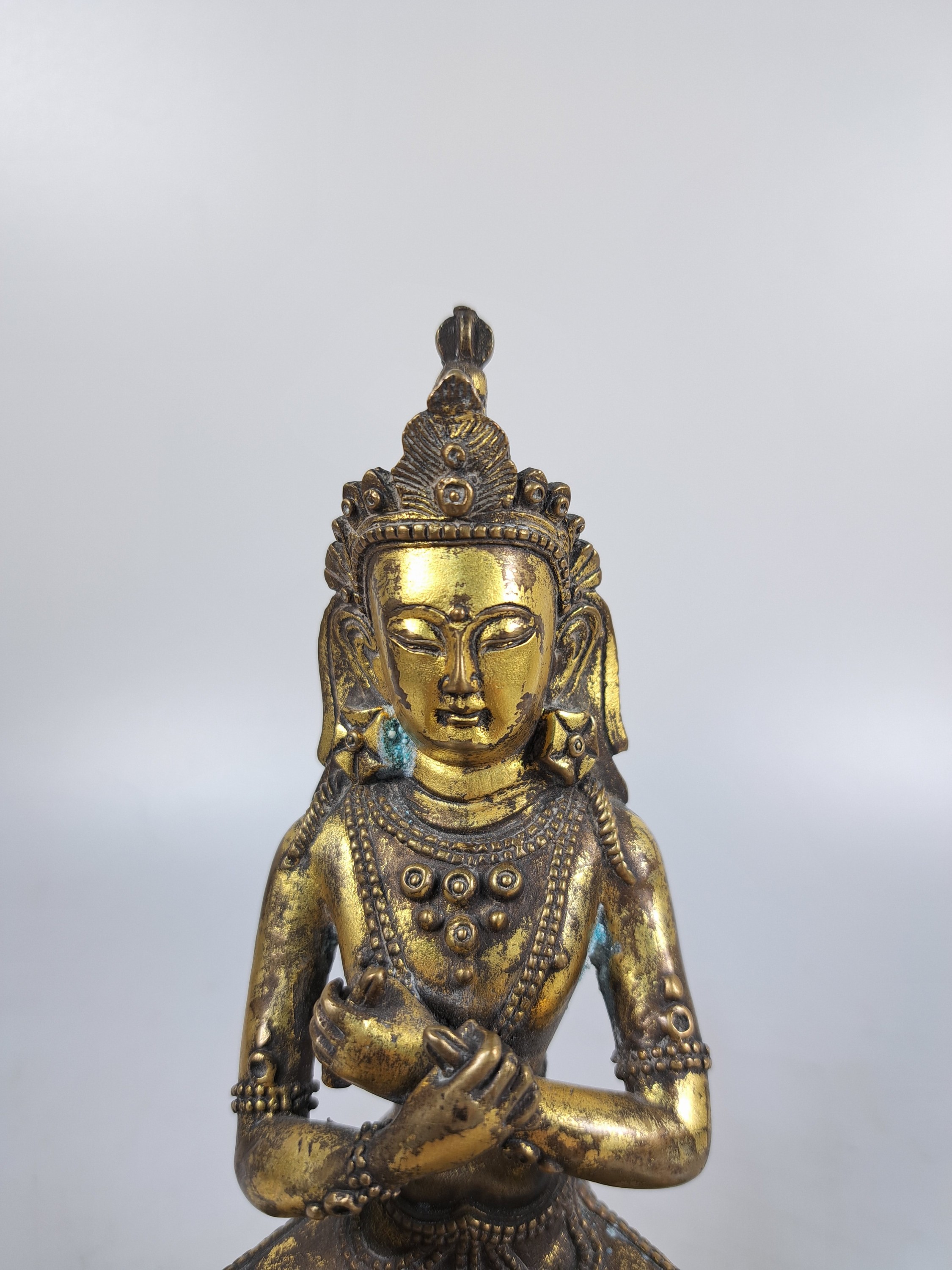 Detail b: Buddha, wohl Tibet, 20. Jh., Bronze, auf doppeltem Lotussockel sitzend, H. ca. 18 cm