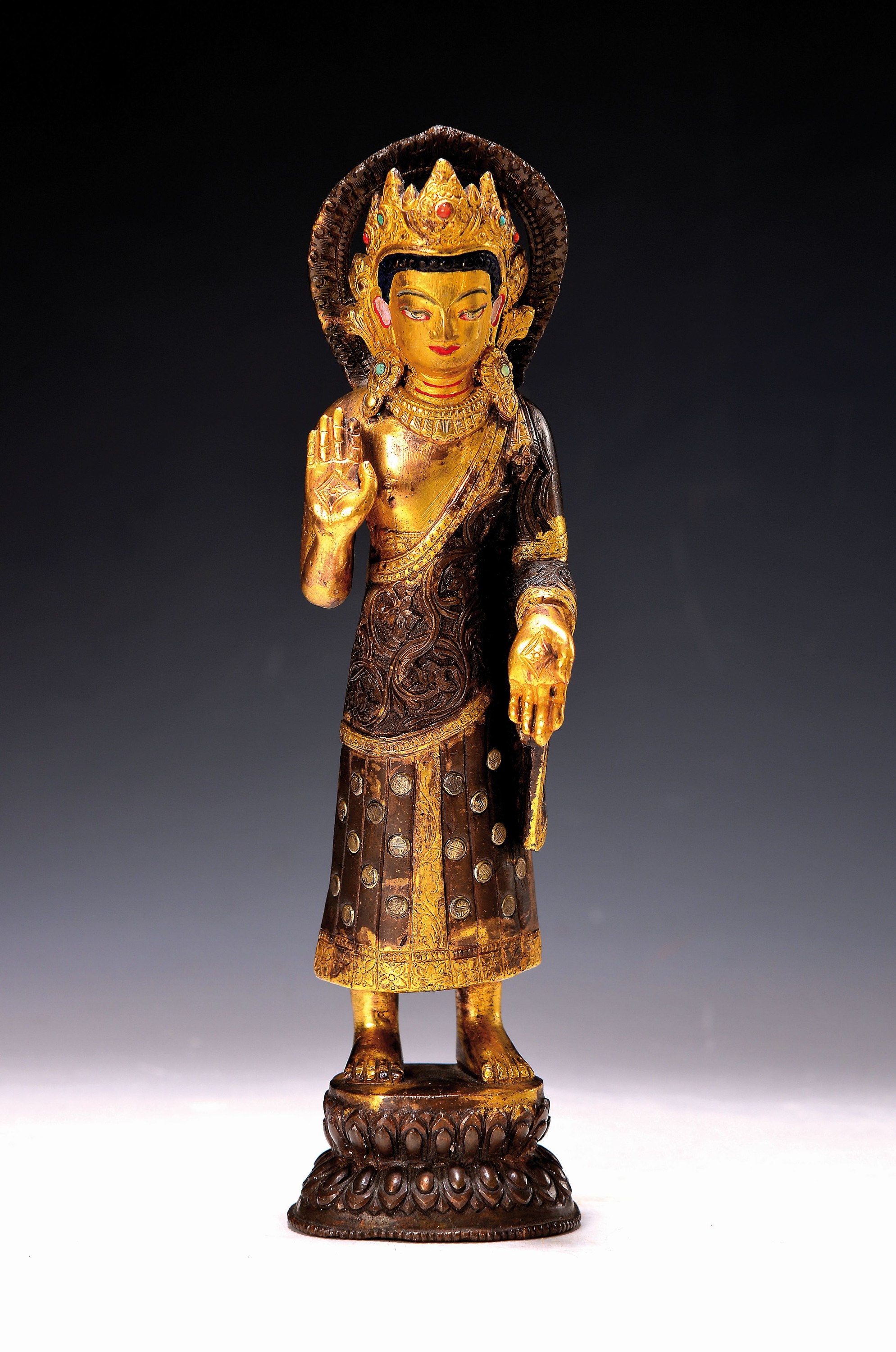 Stehender Buddha, Nepal, 20. Jh., Bronze, patiniert, Gesicht und Haare bemalt, mit Halbedelsteinen besetzt, Geste der Ermutigung, H. ca. 28.5 cm, ...