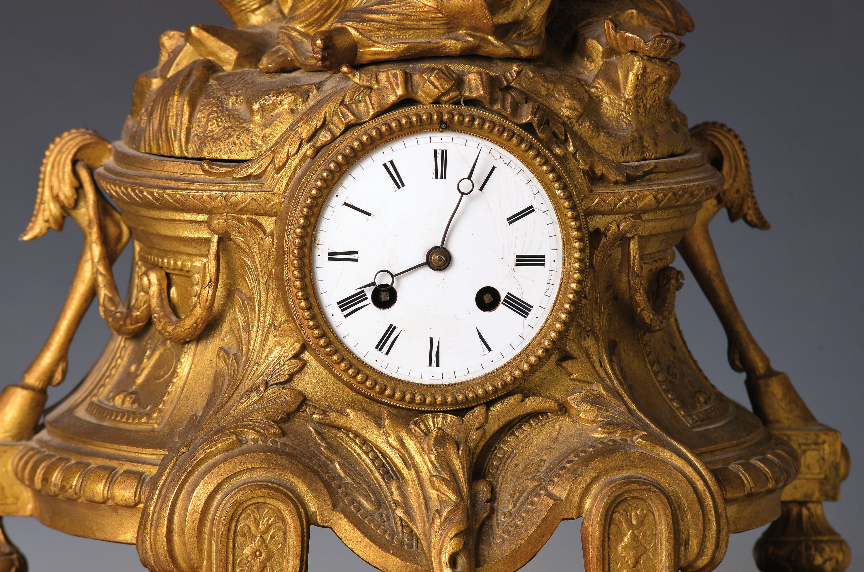 Detail d: Pendule, Frankreich um 1870, Bronzegehäuse, mit Figurenbekrönung mit Sockel, Frau mit Kanne, hintere Füsse verstellbar, mit alter Vergoldung ...