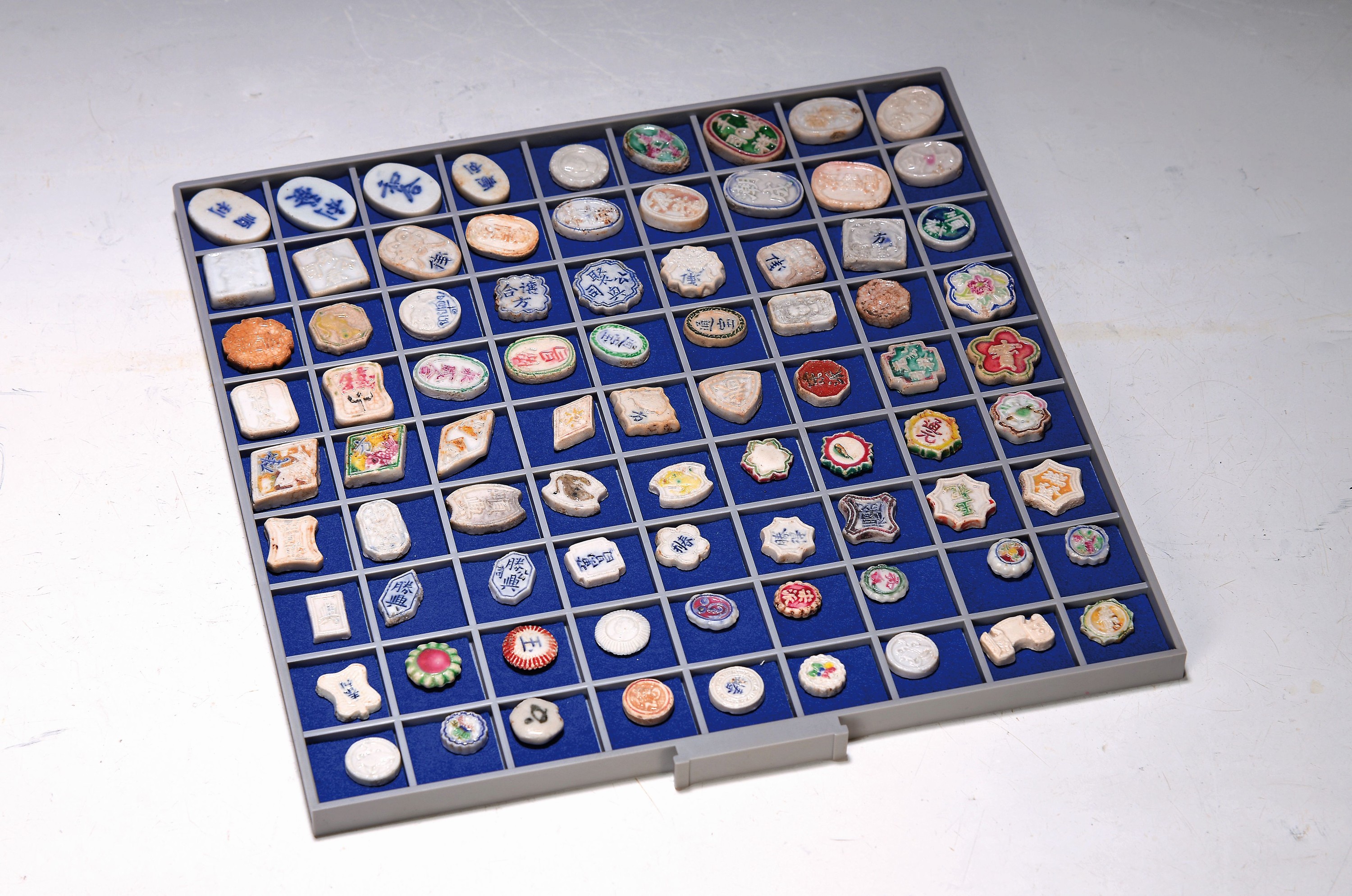 Tablett mit 81 Token/Spielsteine/Jetons, Asien, alle aus Porzellan, teilweise bemalt, teilweise mit Schriftzeichen, Früchten, Fischen etc. ...