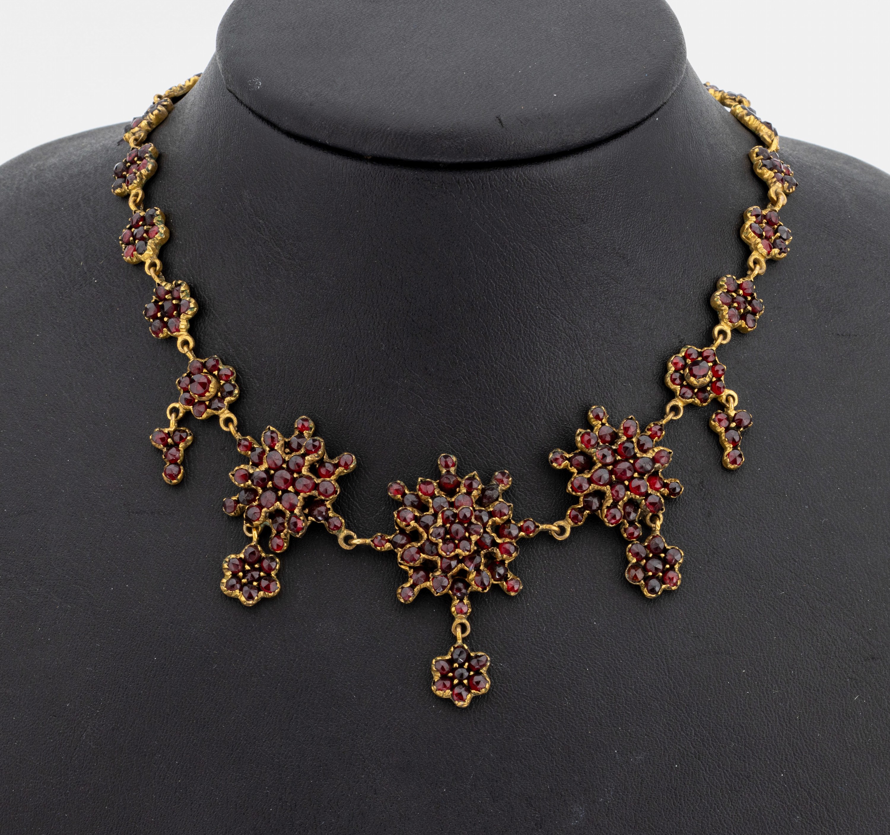 Granatcollier, Böhmen um 1880/90, Tombak verg., blütenförm. Elemente, facett. Granate von intensiver Farbe, L. ca. 40 cm, Federringschließe mit ...