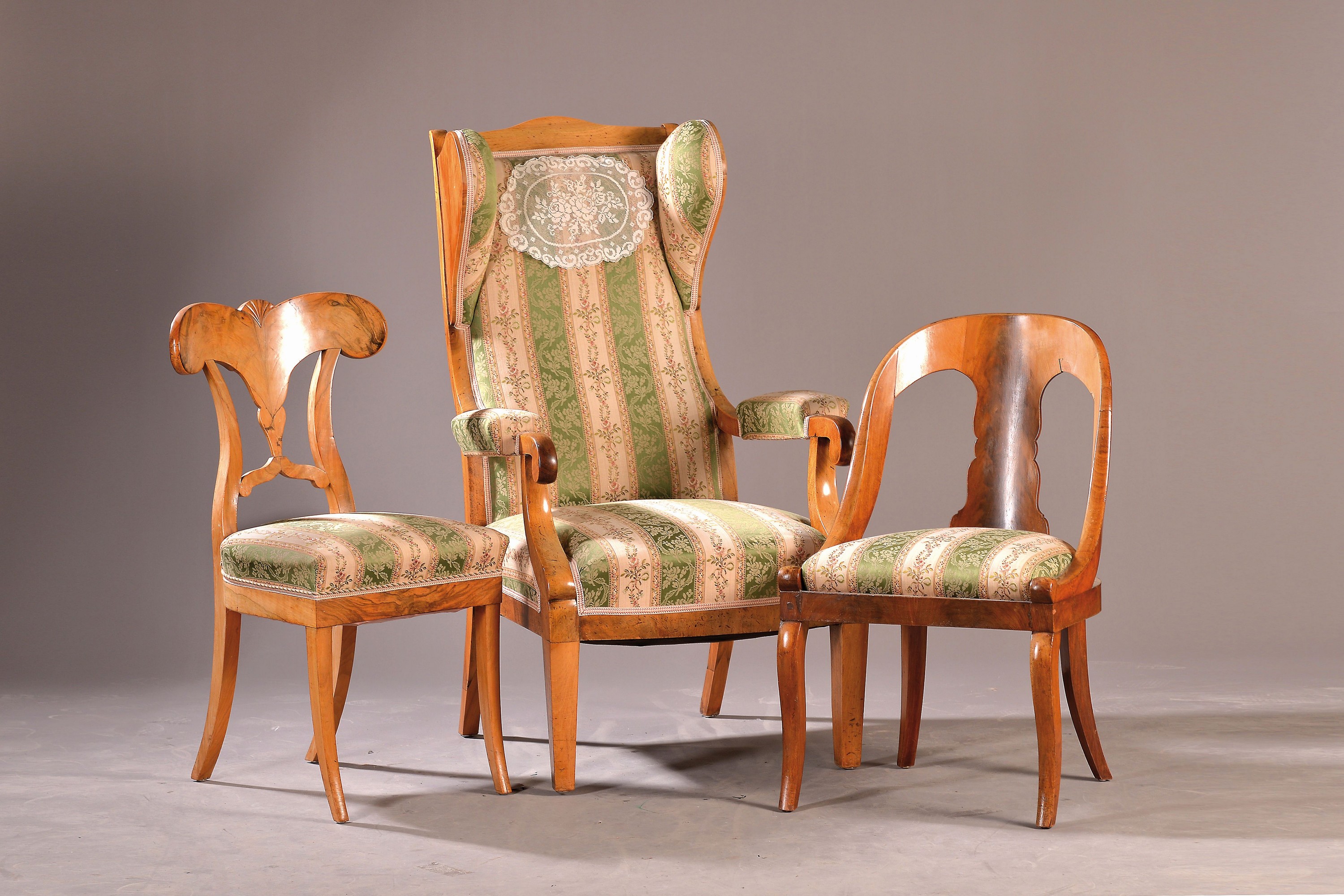 Biedermeier Sitzgarnitur, um 1820-40, best. aus 6 Stühlen (2+3+1), Tisch und Ohrenbackensessel, Nußbaumfurnier z.T. massiv,gepolstert und bezogen, ...