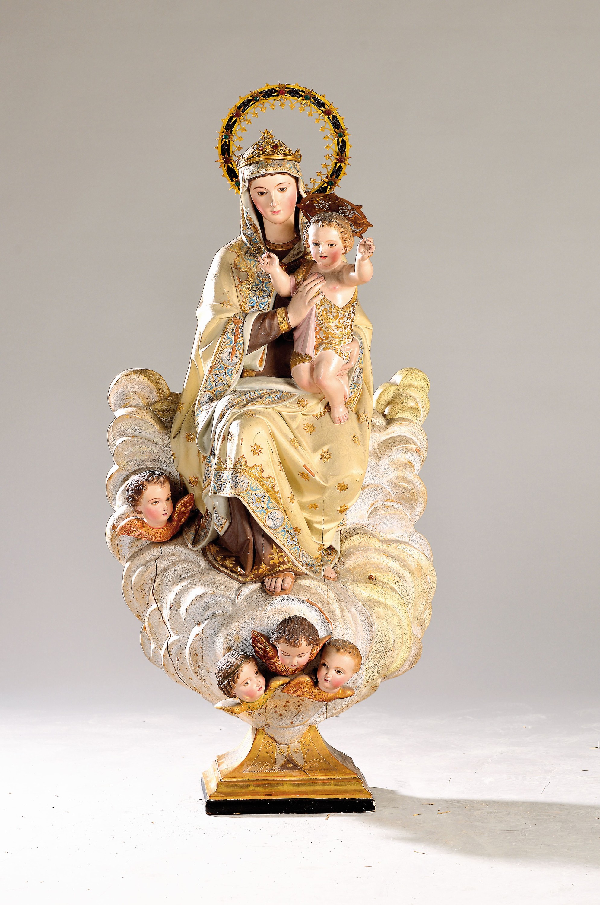 Mutter Gottes mit Kind, wohl Frankreich, um 1900, Holz geschnitzt und gefaßt, mit Engelsköpfen am Sockel und Mantel verziert, ein Engelsköpfchen ...