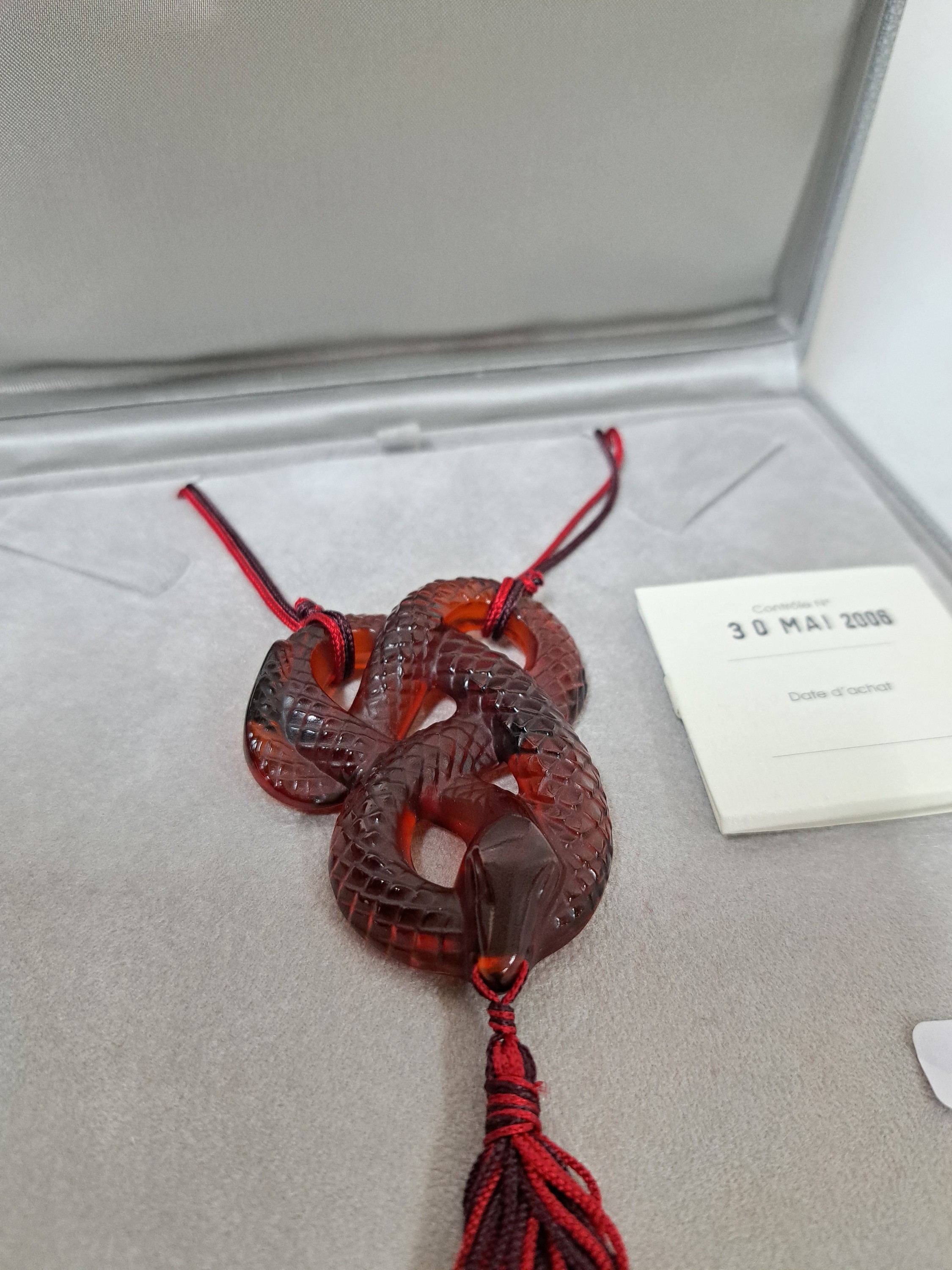 Detail b: Collier Serpent Rouge, Lalique, 20.Jh., rotes Kristallglas in Form einer vielfach gewunden Schlange, z.T. strukturiert, rot- schwarze Seidenquaste im ...
