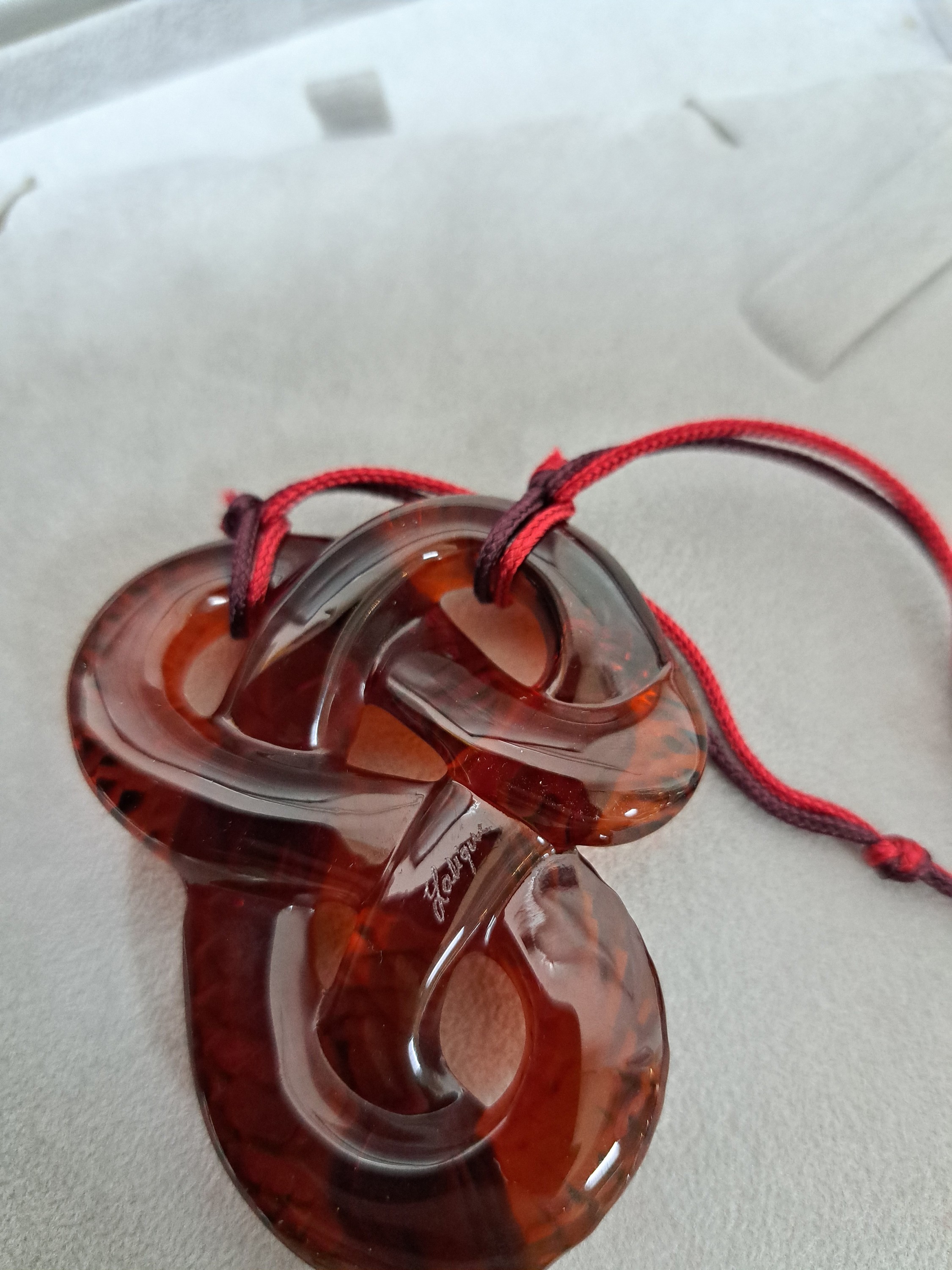 Detail d: Collier Serpent Rouge, Lalique, 20.Jh., rotes Kristallglas in Form einer vielfach gewunden Schlange, z.T. strukturiert, rot- schwarze Seidenquaste im ...