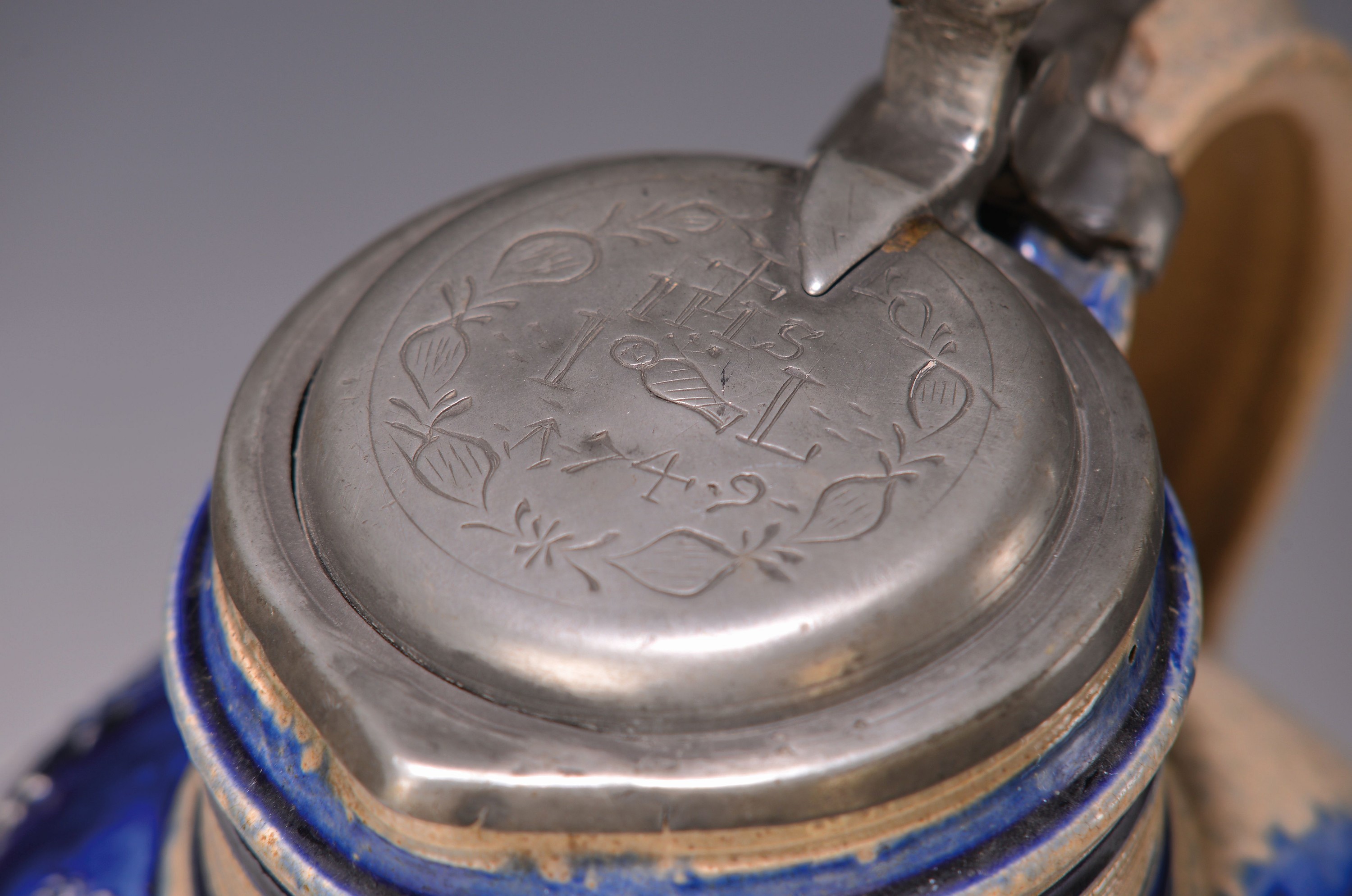 Detail a: Kugelbauchkrug, Westerwald, dat. 1749, Steinzeug, dreiseitiges Wappen, reich verziert, blaue Bemalung, orig. Zinndeckel mit IHS und Datierung, H. ca. ...