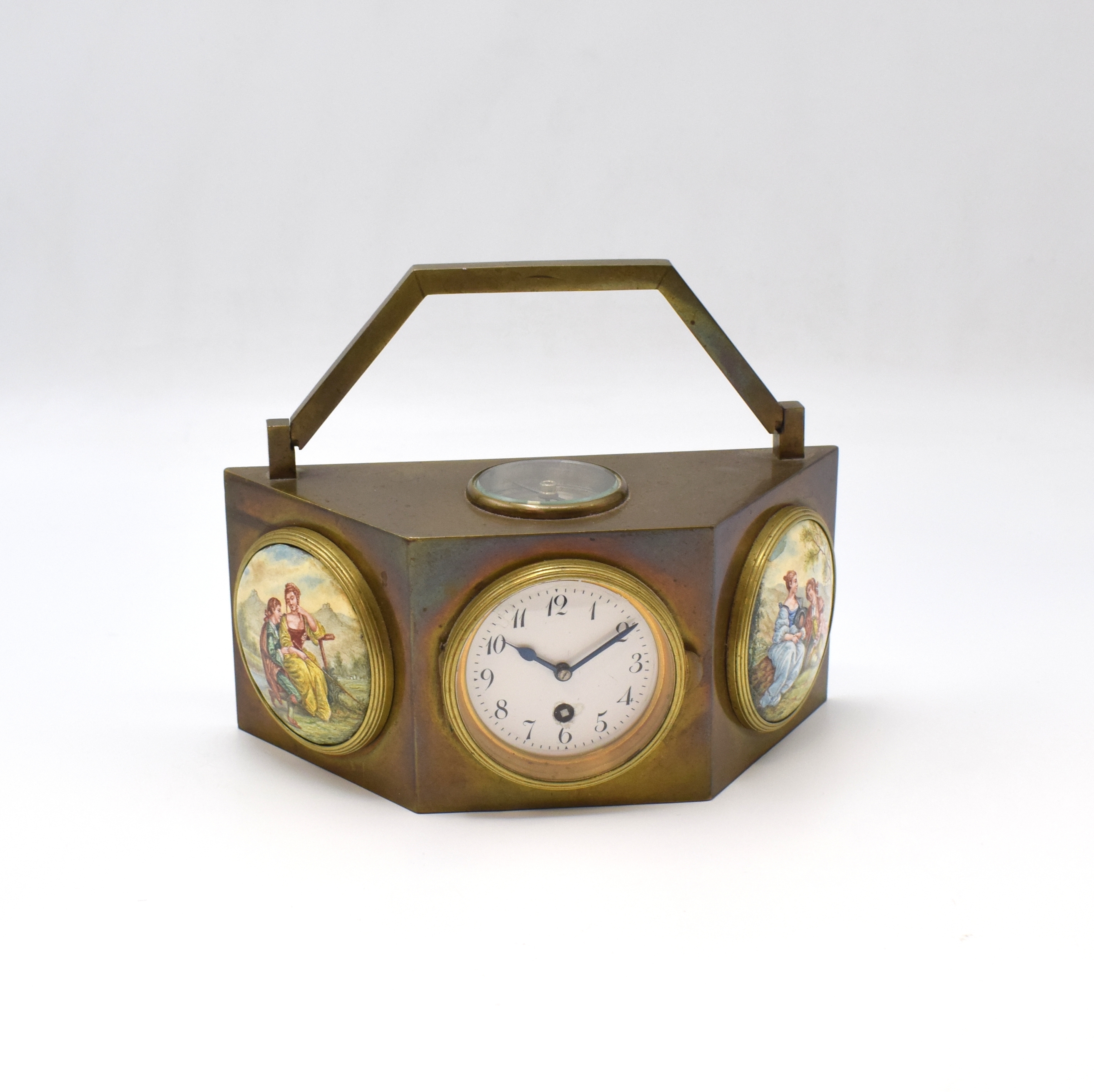 Reiseuhr aus Bronze, um 1900, polygonales Gehäuse, in der Mitte die Uhr, Emailzifferbl. m. arab. Std. riss., gebl. Stahlz., links und rechts ...