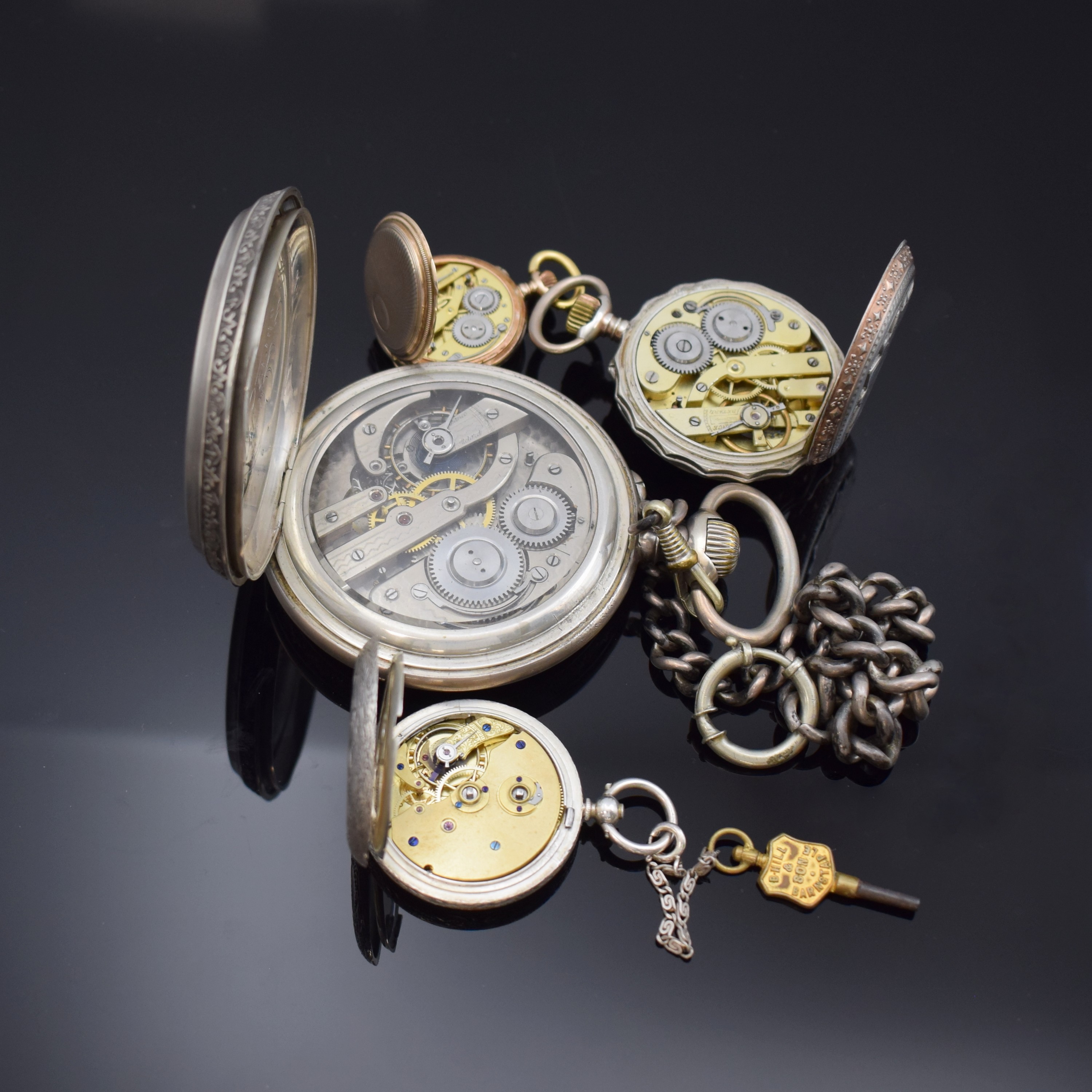 Detail e: 4 Taschenuhren in Silber, 1 x davon übergroßan Kette, Cuv. im Innern mit Eigentümergravur, reich graviertes und floral verziertes Gehäuse, Boden ...