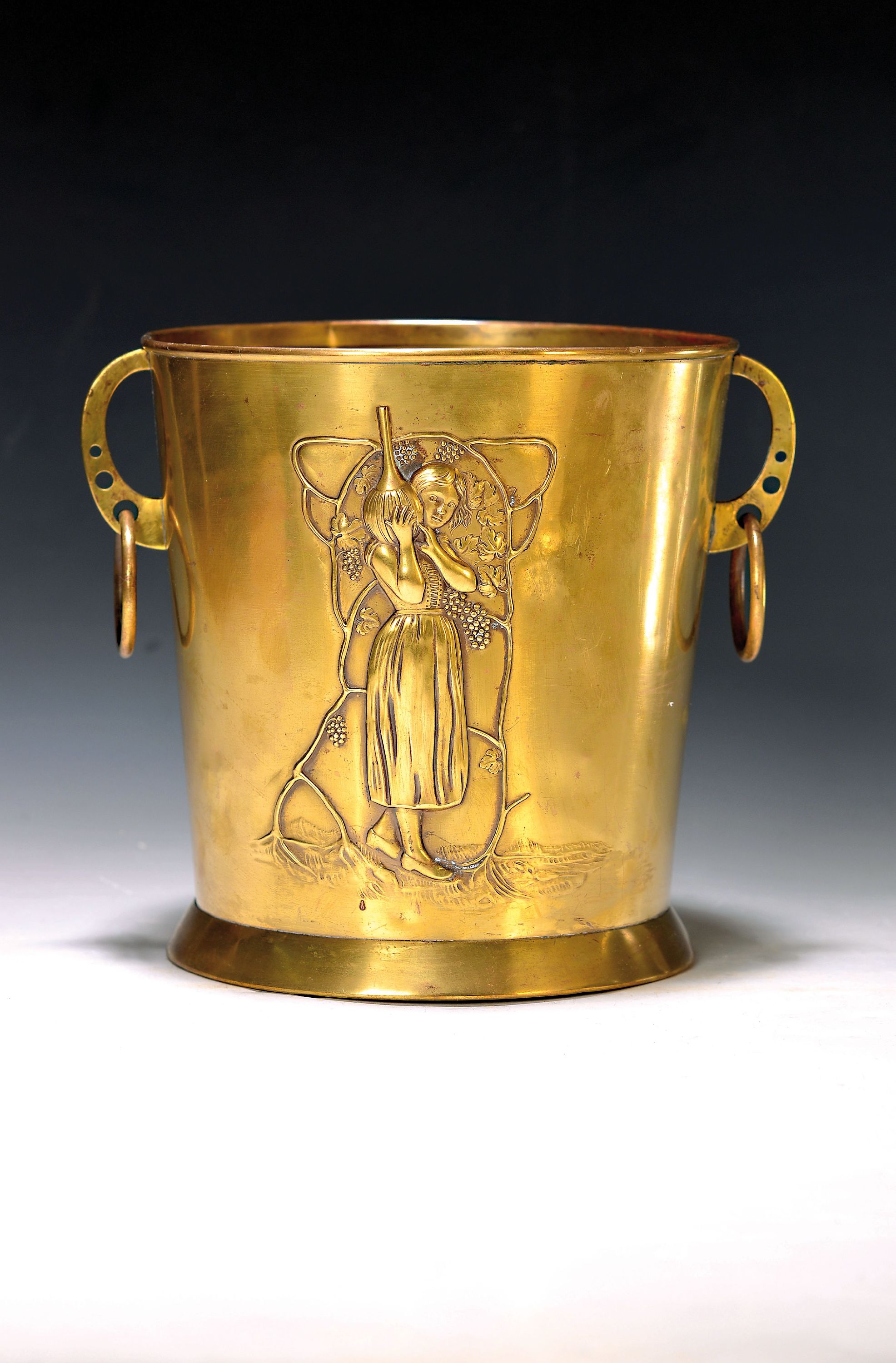 Weinkühler, deutsch, WMF, um 1900, Messing, Front reliefiert mit Winzerin mit bauchiger Flasche, H. ca. 20.5cm, altersbedingt leicht verbeult