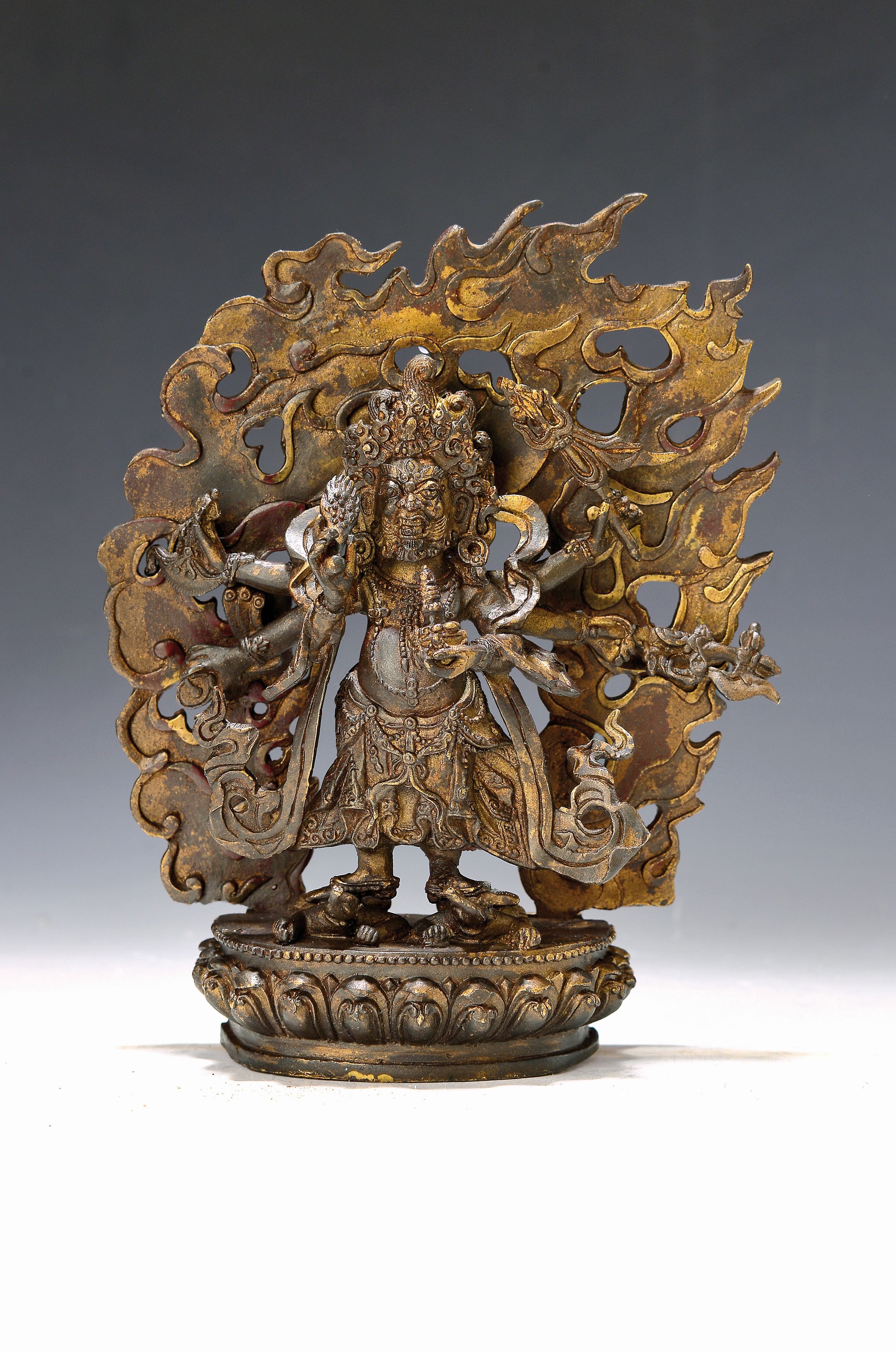 Mahakala mit Dreizackstab, Nepal, Mitte 20. Jh., Kupferlegierung vergoldet, mit Vajra-Axt, Sichelmesser und weiteren Attributen, er steht auf ...