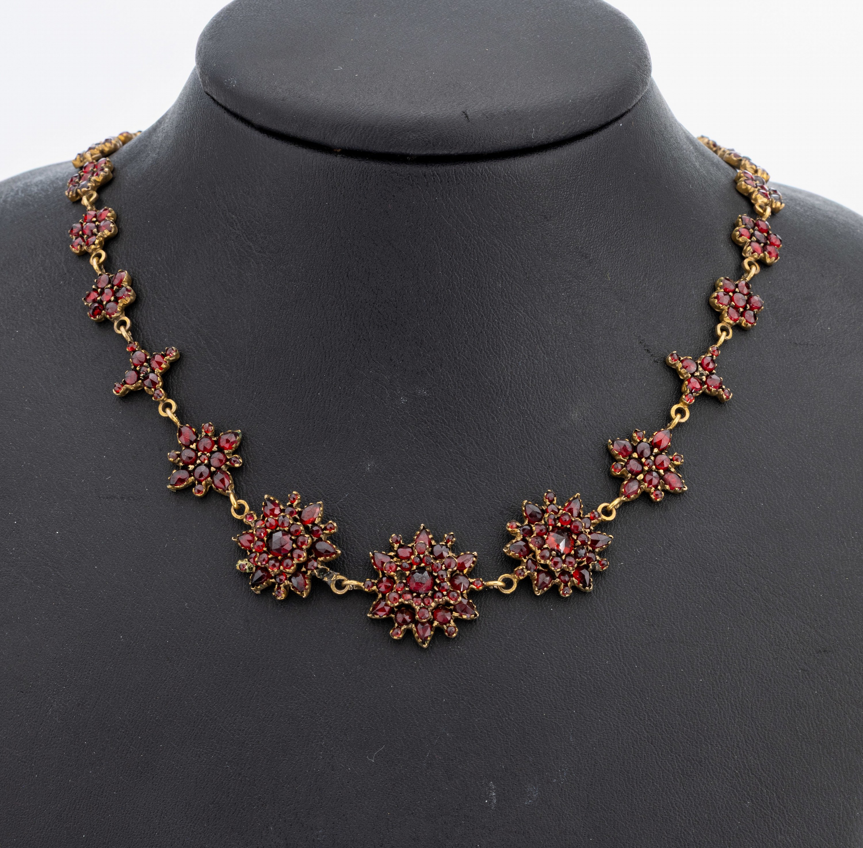Granatcollier, Böhmen um 1880, Tombak, florale Elemente, bes. mit rundfacett. Granaten von schöner Farbe, L. ca. 45 cm, Federringschließe