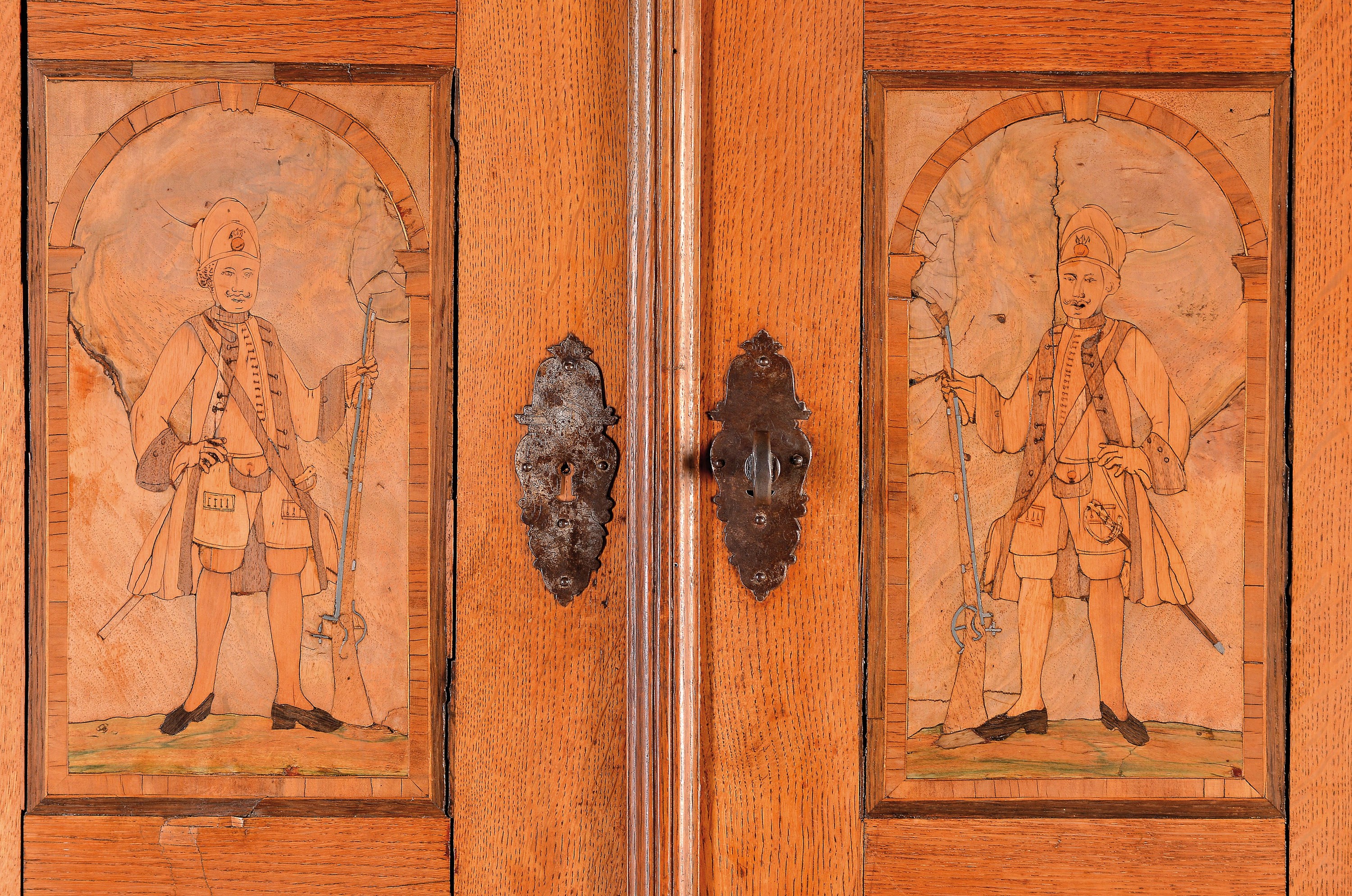 Detail a: Stollenschrank, Barock, um 1760-70, Eiche massiv, teilweise Nussbaumfurnier, zwei Türen mit Intarsienbildern eingelegt, stehende Soldaten, Unterbau ...