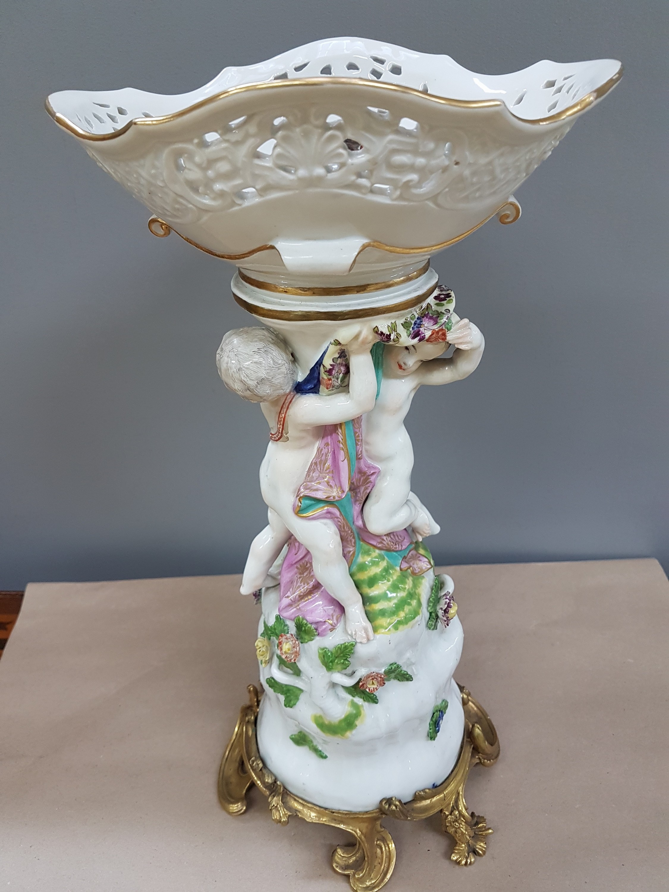 Detail b: Figürlicher Tafelaufsatz, Meissen, um 1740, zwei Putten auf stammähnlichem Sockel stehend mit Geäst und applizierten Blüten, Korbschale mit ...
