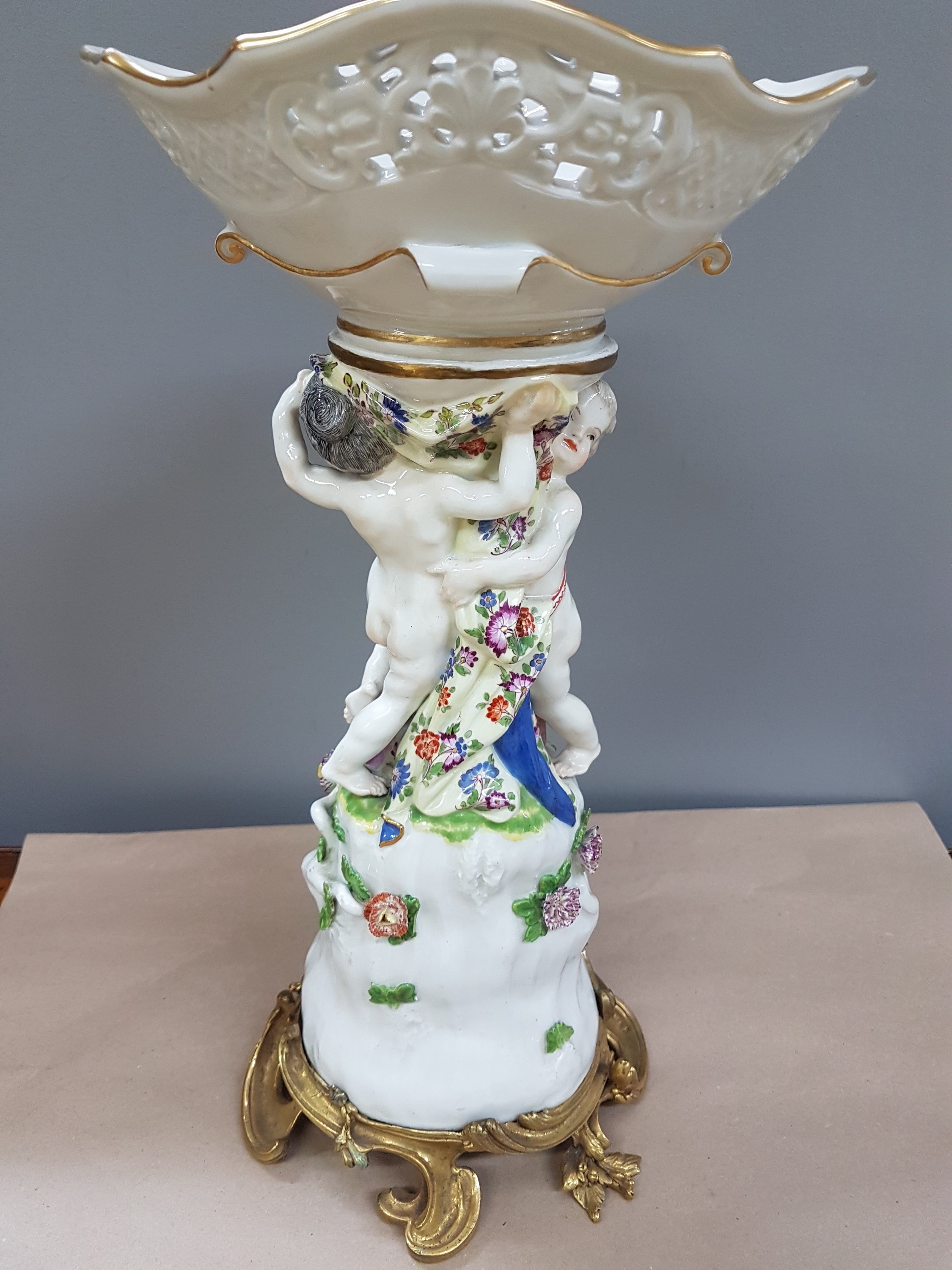 Detail g: Figürlicher Tafelaufsatz, Meissen, um 1740, zwei Putten auf stammähnlichem Sockel stehend mit Geäst und applizierten Blüten, Korbschale mit ...