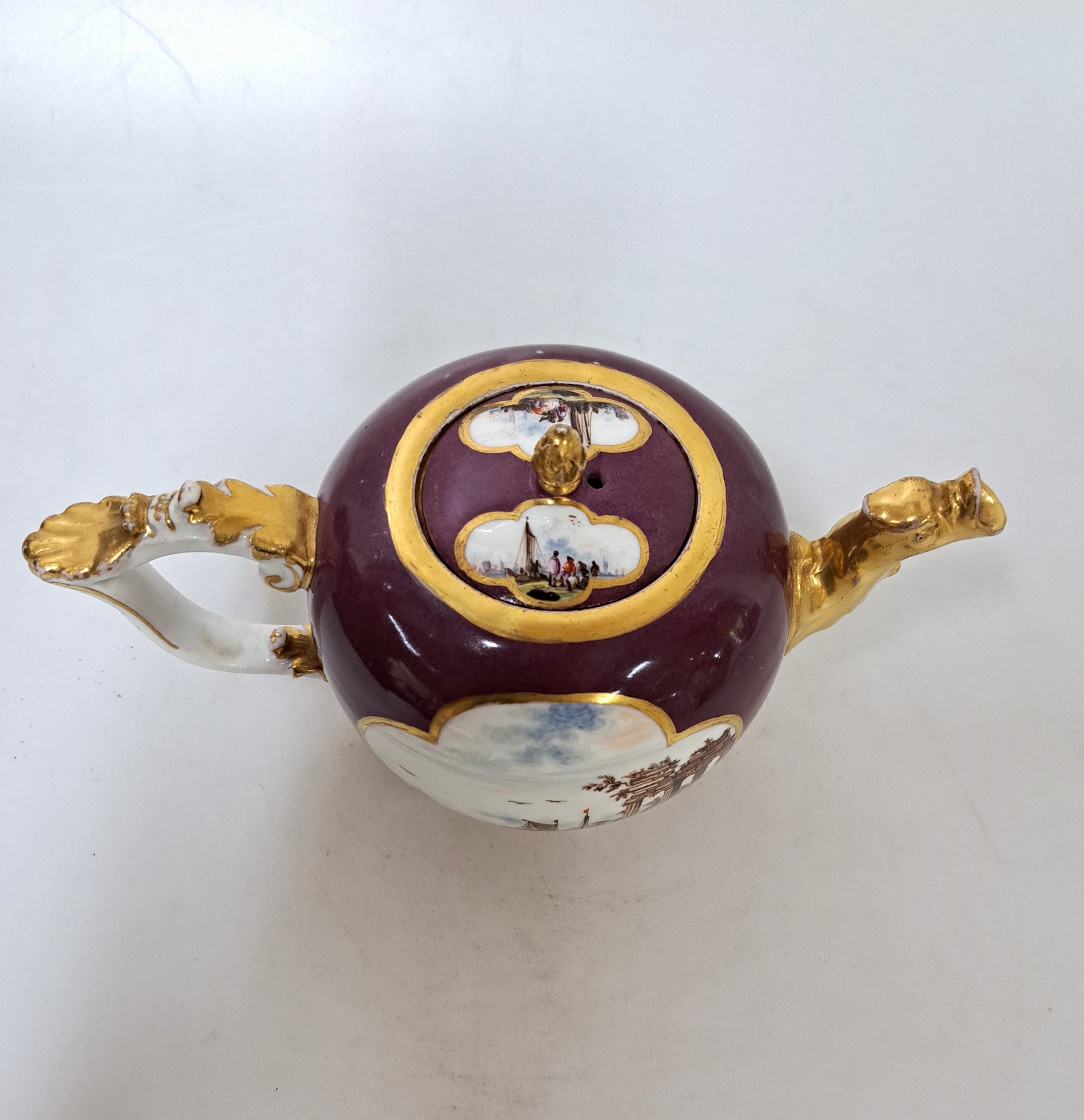 Detail b: Teekanne, Meissen, um 1735, Porzellan, bordeauxfarbener Fond, Tierkopfausguss, geschweifter Henkel mit Muschel, beidseitig vierpassige Aussparung mit ...