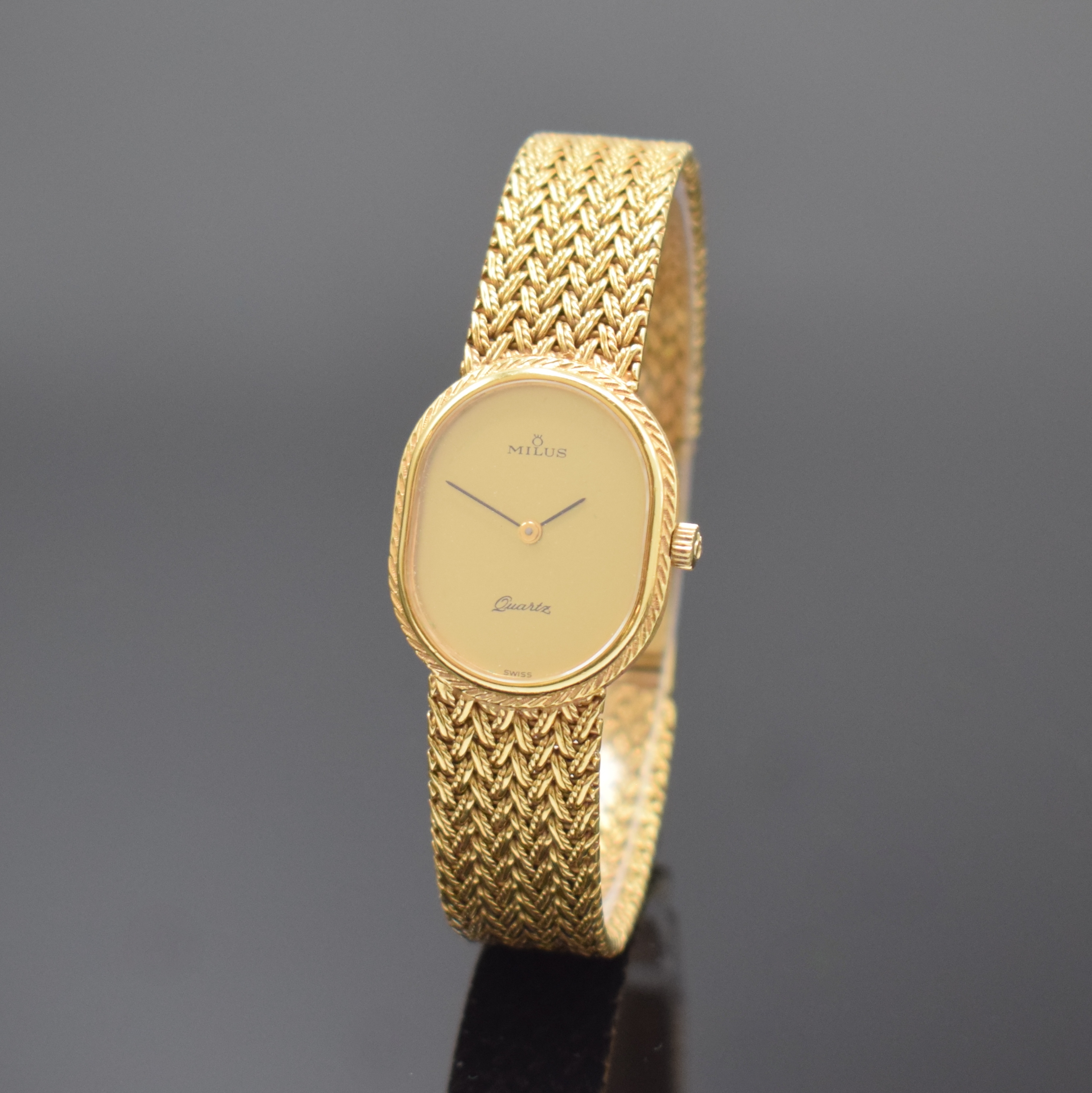 MILUS Damenarmbanduhr in GG 750/000, Schweiz um 1975, quarz, Boden aufgedr., orig. Gold- Flechtband, gold. Zifferbl. m. schwarzen Zeigern, M. 27 x ...