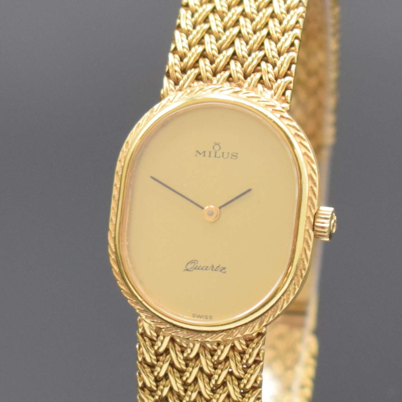 Detail a: MILUS Damenarmbanduhr in GG 750/000, Schweiz um 1975, quarz, Boden aufgedr., orig. Gold- Flechtband, gold. Zifferbl. m. schwarzen Zeigern, M. 27 x ...
