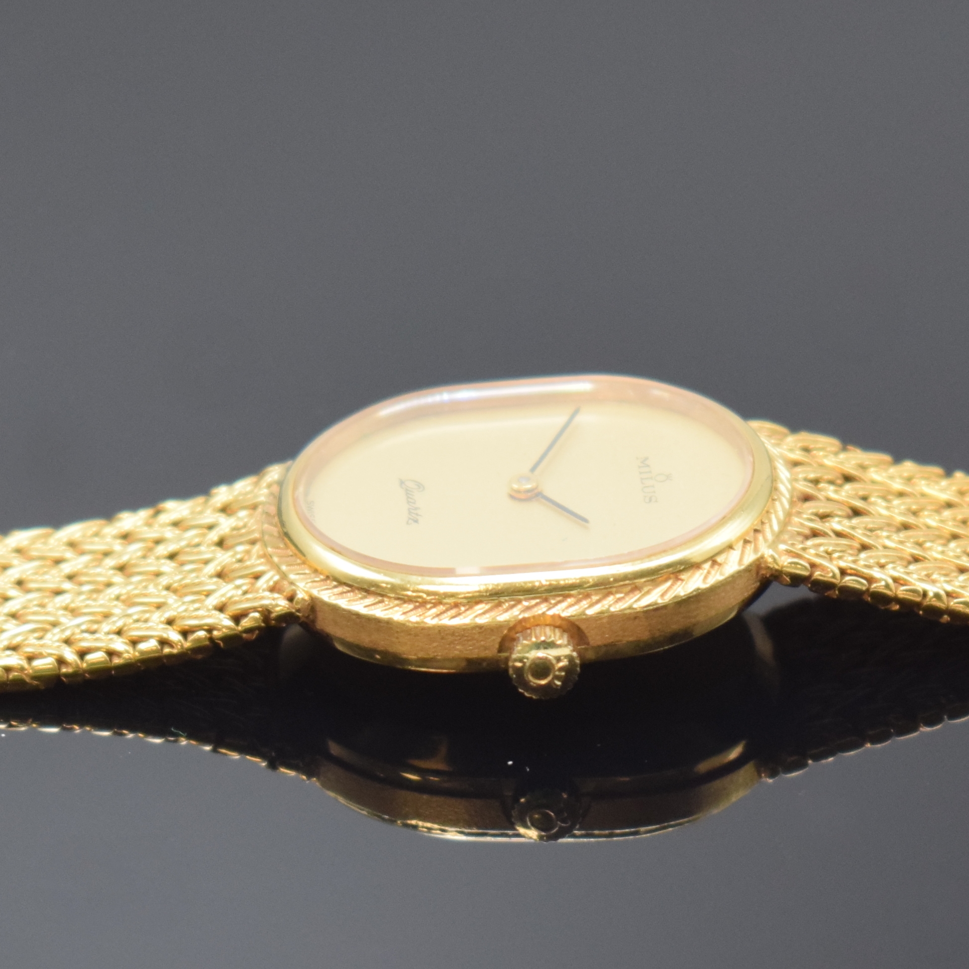 Detail d: MILUS Damenarmbanduhr in GG 750/000, Schweiz um 1975, quarz, Boden aufgedr., orig. Gold- Flechtband, gold. Zifferbl. m. schwarzen Zeigern, M. 27 x ...