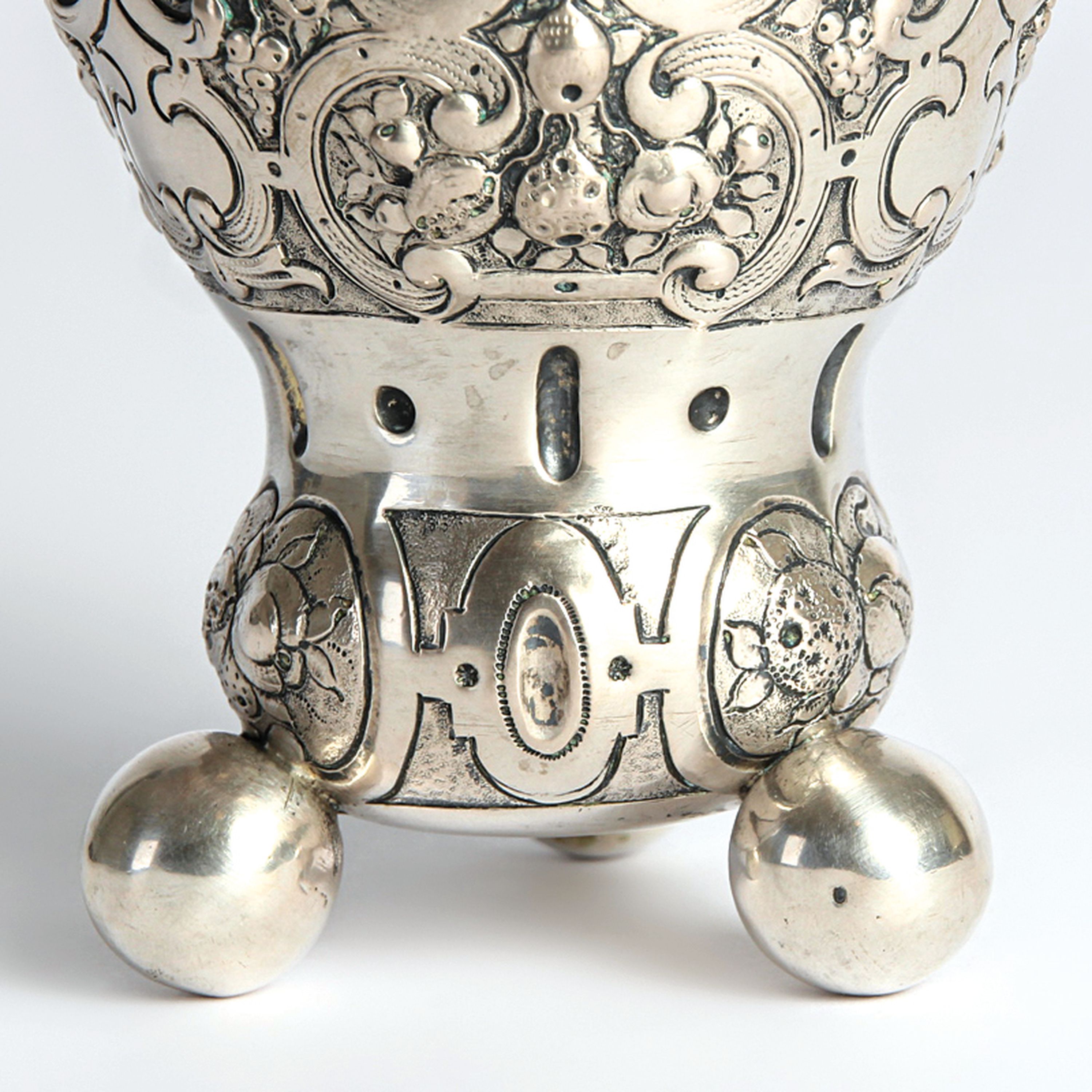 Detail b: Kugelfußbecher, Nürnberg, 18.Jh., 13 Lot Silber, Dekor mit Rollwerk und Früchten, auf drei großen Kugelfüßen, 119g, H. 10 cm, Meistermarke N