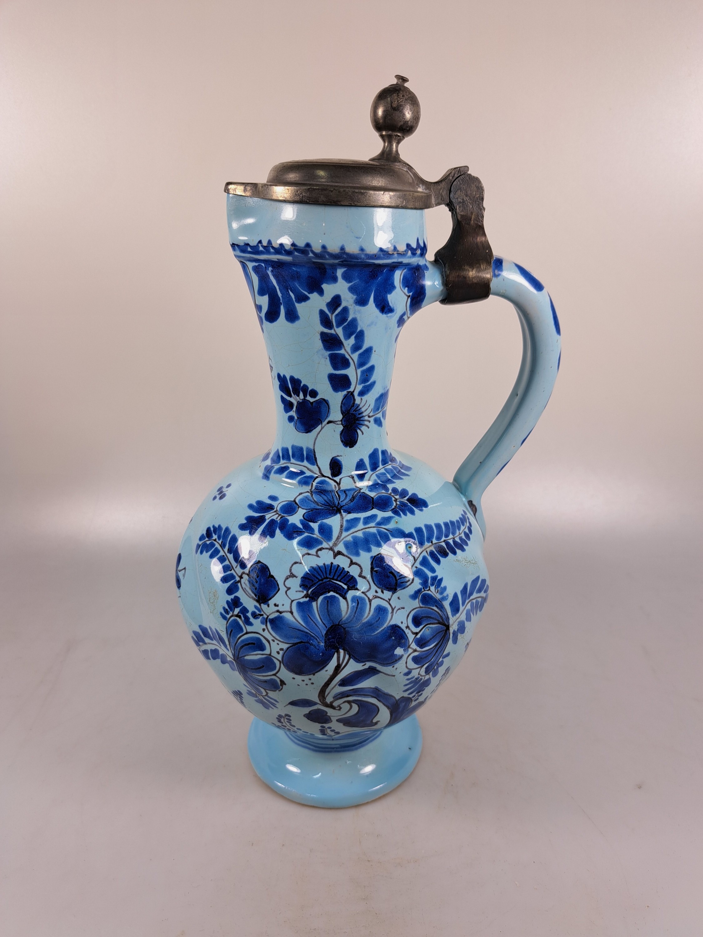 Detail c: Enghalskrug, Hanau, um 1740, Fayence, Drehermarke E, hellblauer, Grund mit blauer Blumenbemalung, rest., Zinndeckel, H. ca.31 cm