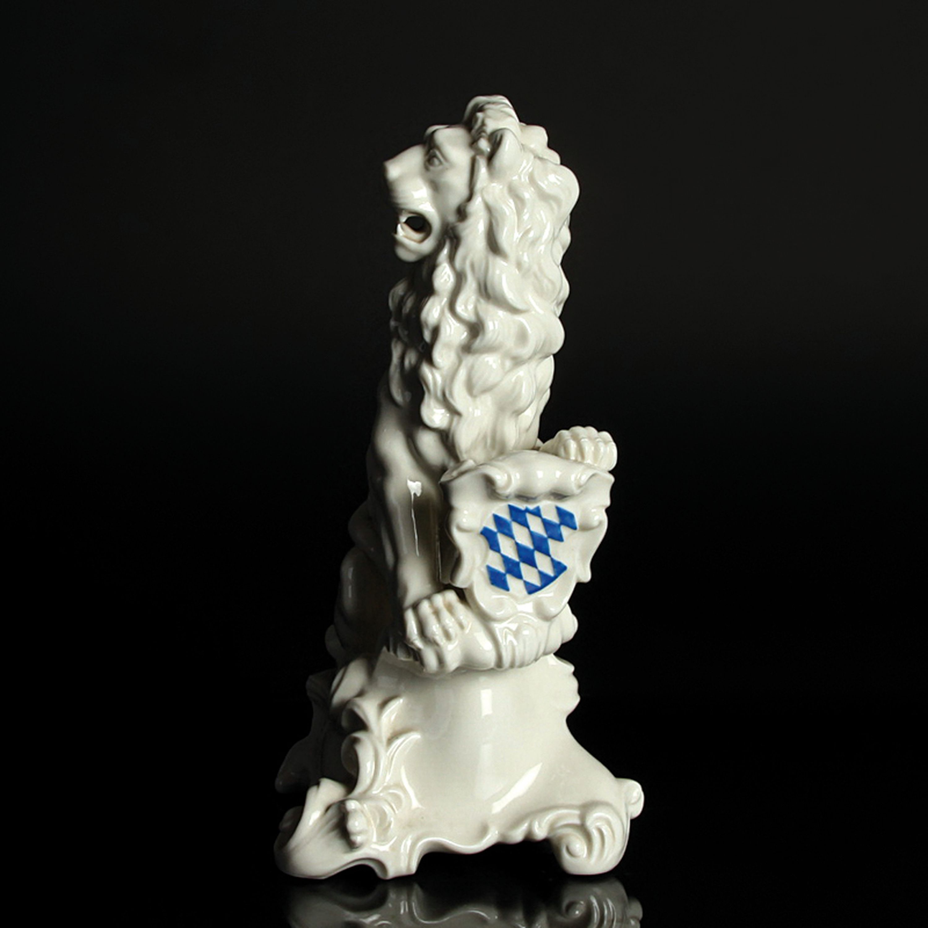 Detail c: Porzellanfigur bayerischer Löwe, Nymphenburg, 20.Jh., Entw. J. Wackerle, Weißporzellan, blau staffiertes Wappenschild, am Boden signiert, H. 23 cm