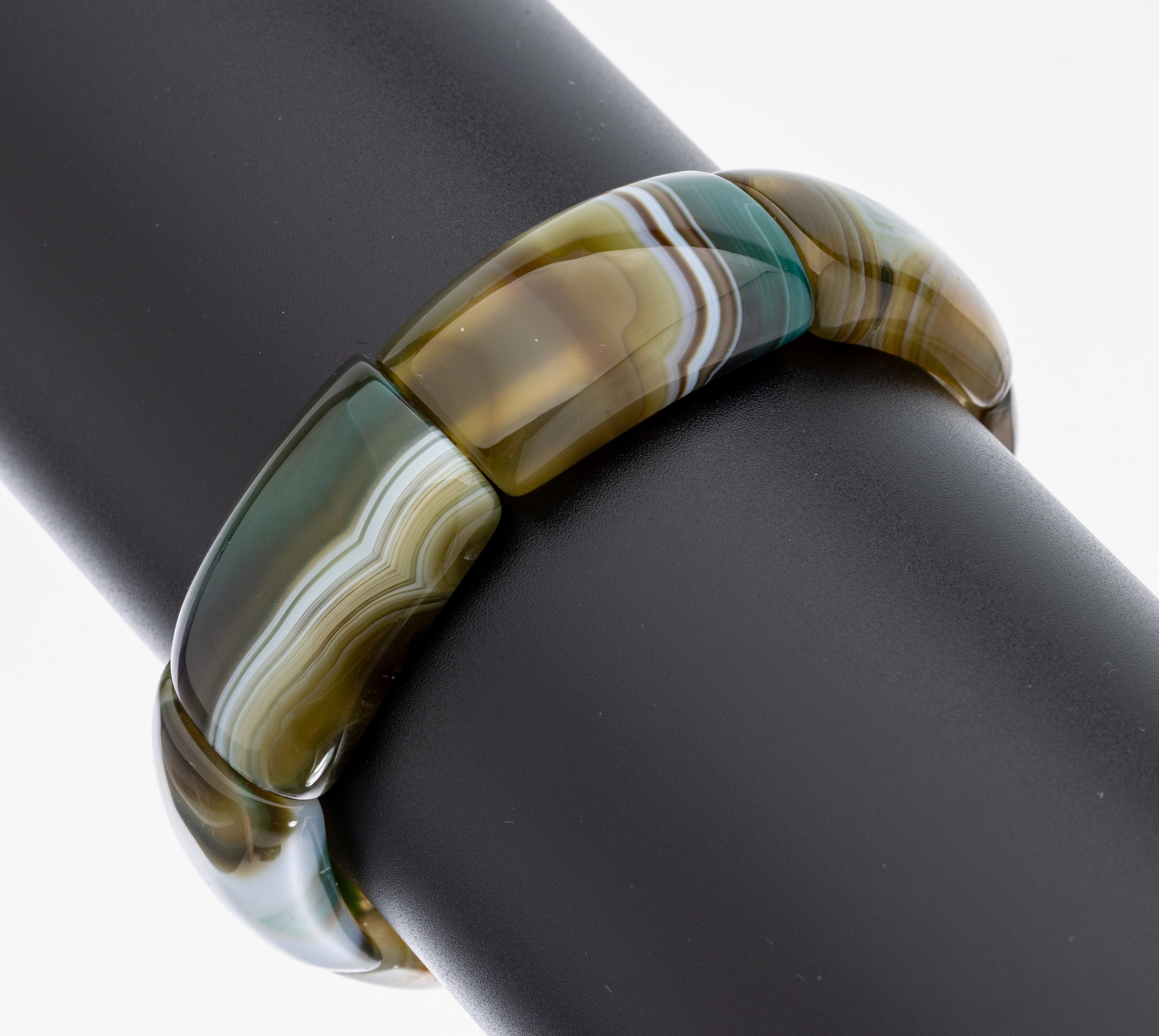 Achat-Armreif, Idar-Oberstein um 1900, Streifenachat grün/braun/beige, 7 einzelne gewölbte Glieder auf Gummiband aufgezogen, min. best., D. ca. ...