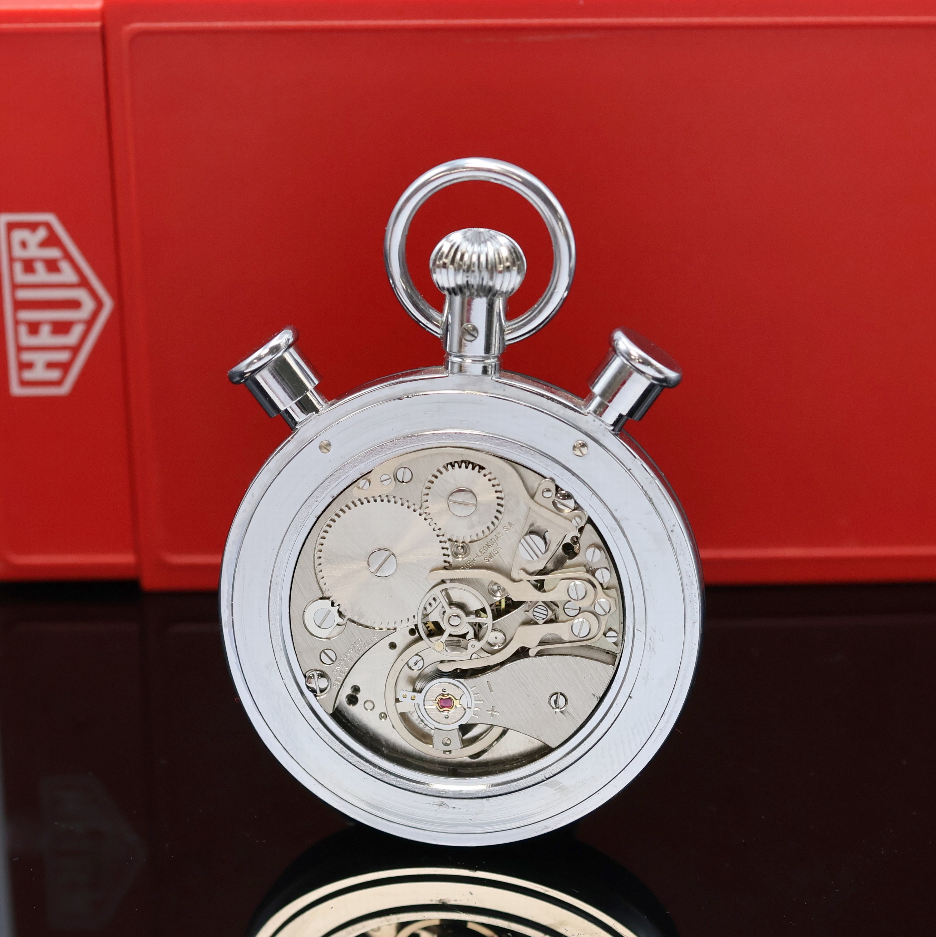 Detail c: HEUER Rattrapante-Stoppuhr in original Box, Schweiz um 1970, verchr. Geh. teilw. schwarz matt., Boden aufgedr., weißes Zifferbl. m. 100er Teilung ...