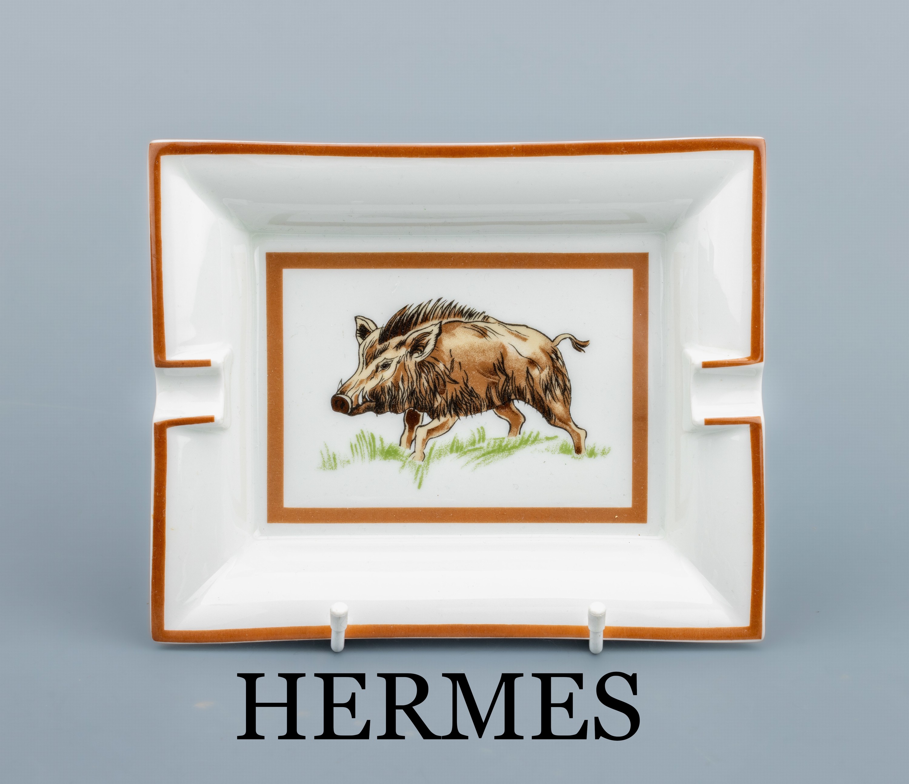 HERMES Aschenbecher, Porzellan, weißer Fond mit Darstellung eines Wildschweins, braune Zierstreifen, Boden mit Velourleder, ca. 19 x 15 cm, sign.