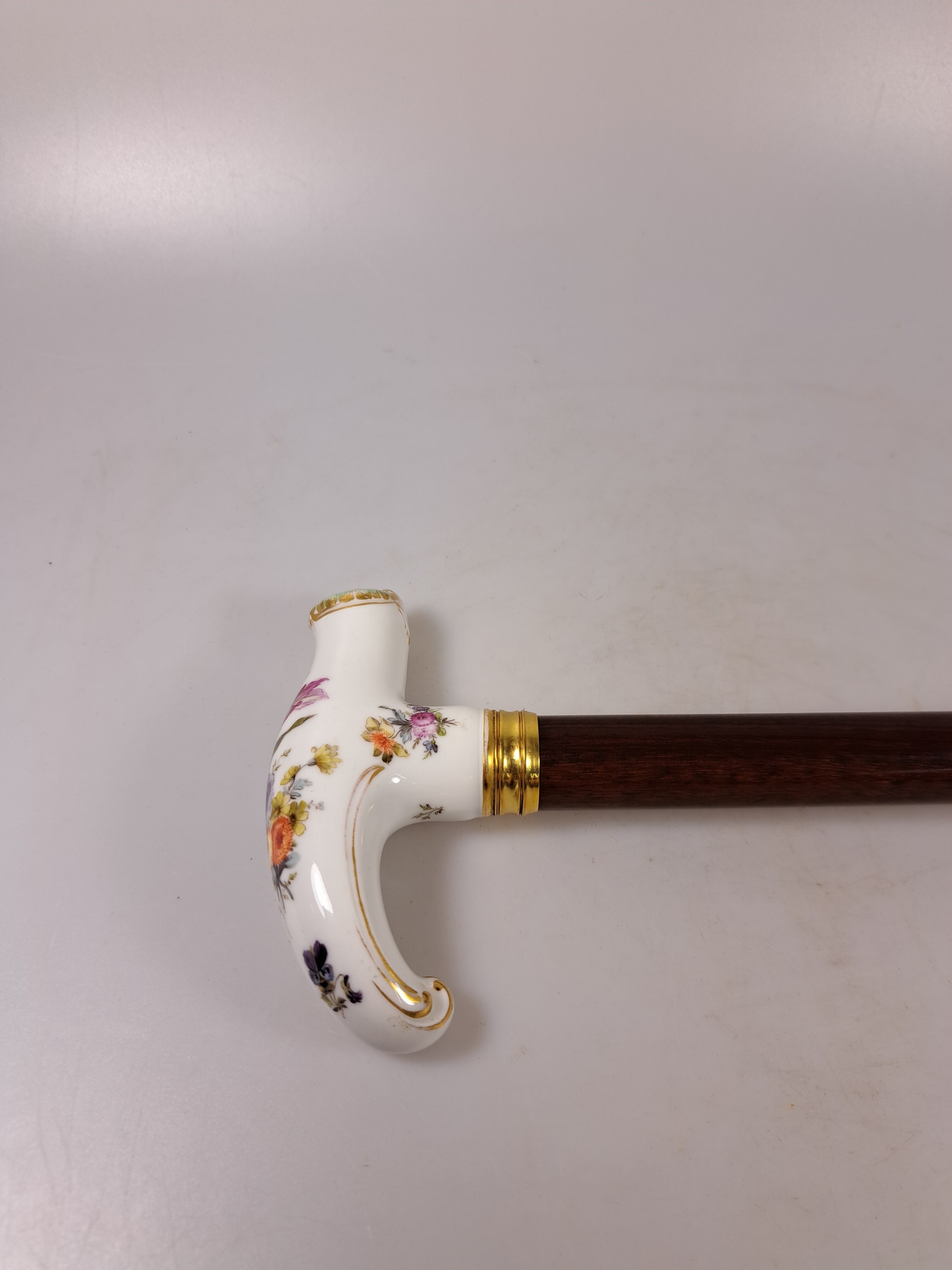Detail a: Flanierstock mit Porzellangriff, Griff mit feiner Blumenmalerei, in geschwungener barocker Form, Goldstaffage, vergoldete gerillte Manschette, Schuß ...