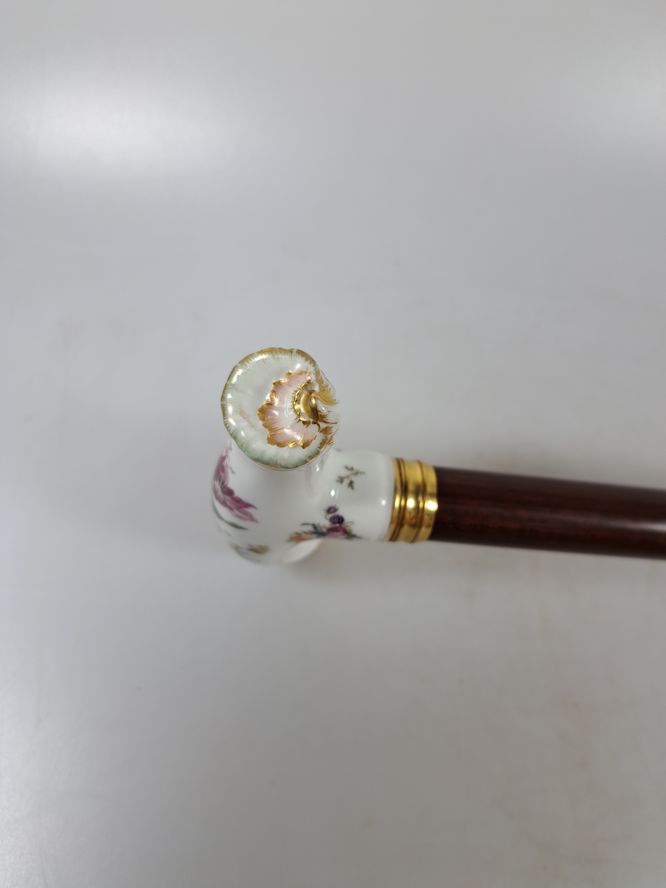 Detail b: Flanierstock mit Porzellangriff, Griff mit feiner Blumenmalerei, in geschwungener barocker Form, Goldstaffage, vergoldete gerillte Manschette, Schuß ...