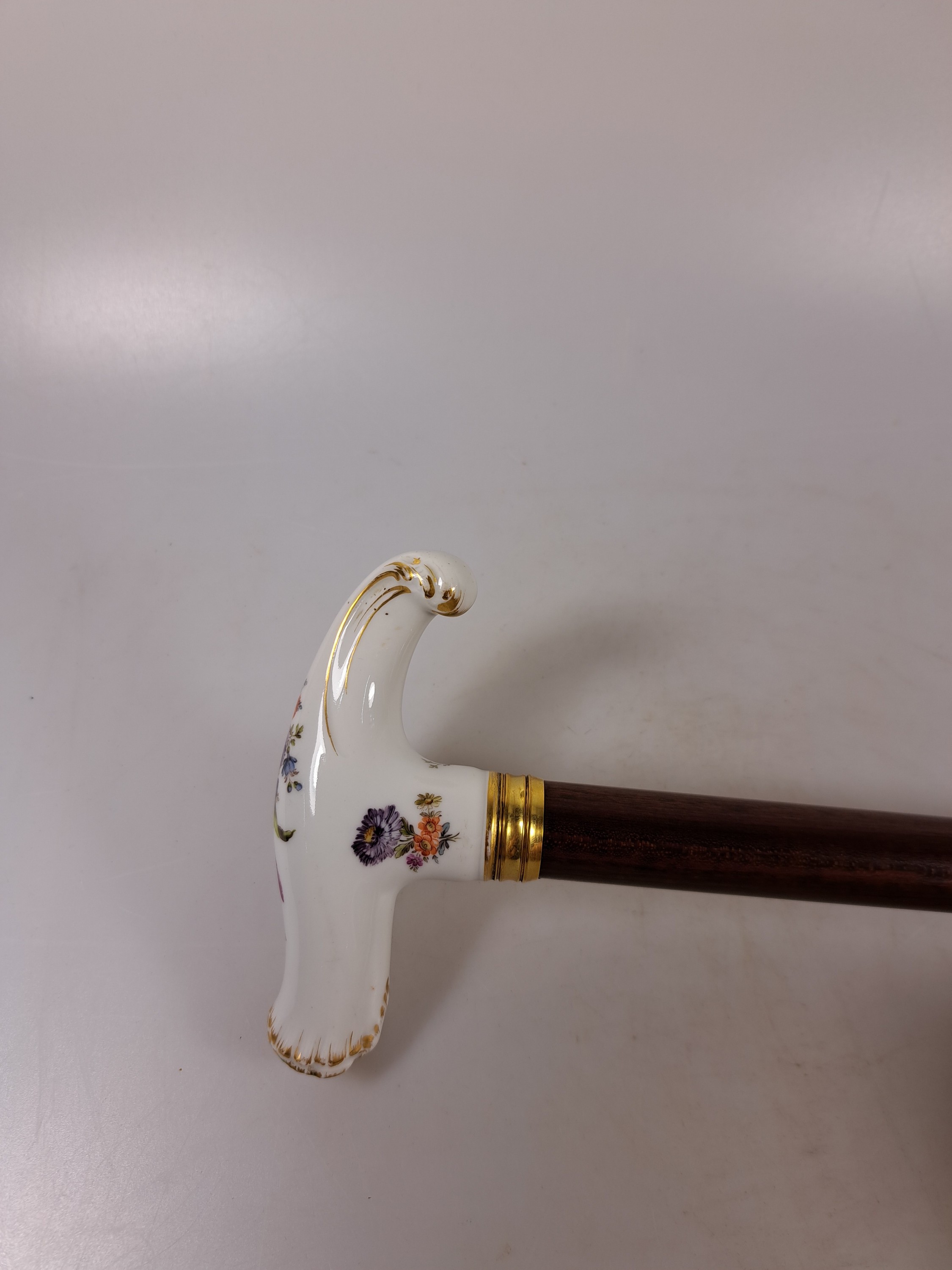 Detail c: Flanierstock mit Porzellangriff, Griff mit feiner Blumenmalerei, in geschwungener barocker Form, Goldstaffage, vergoldete gerillte Manschette, Schuß ...