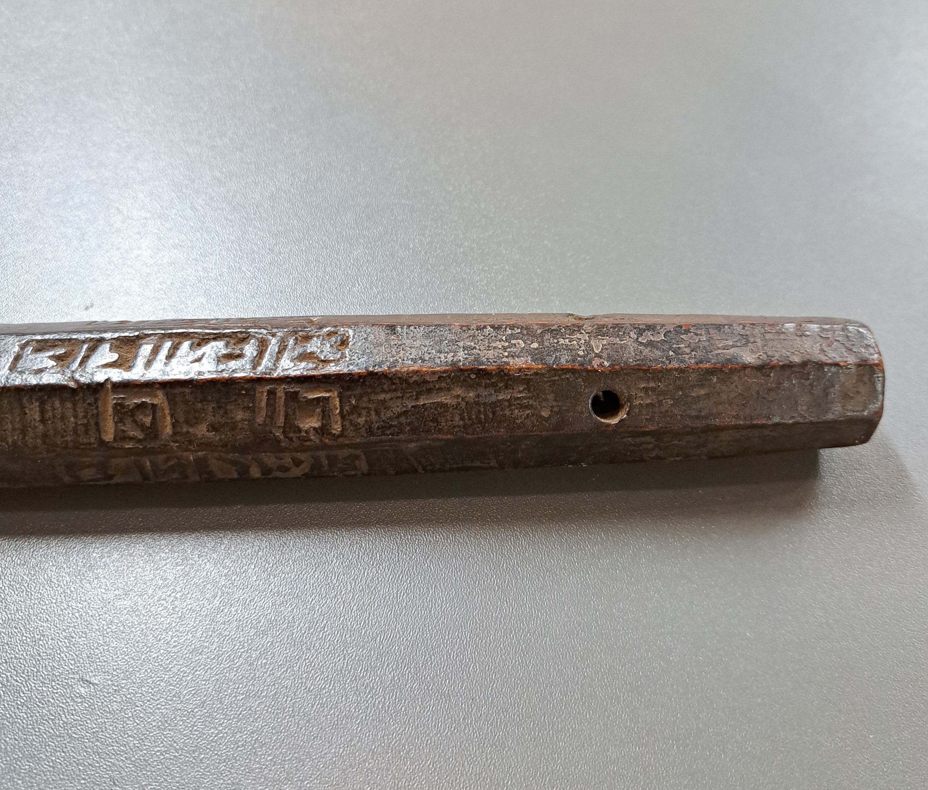 Detail a: Tibetanischer Schäferstock als Sonnenuhr, aus einem Stück Holz gehauen, dunkel, achtkantig, jede Seite verschiedene Buchstaben u. Löcher, die, ...