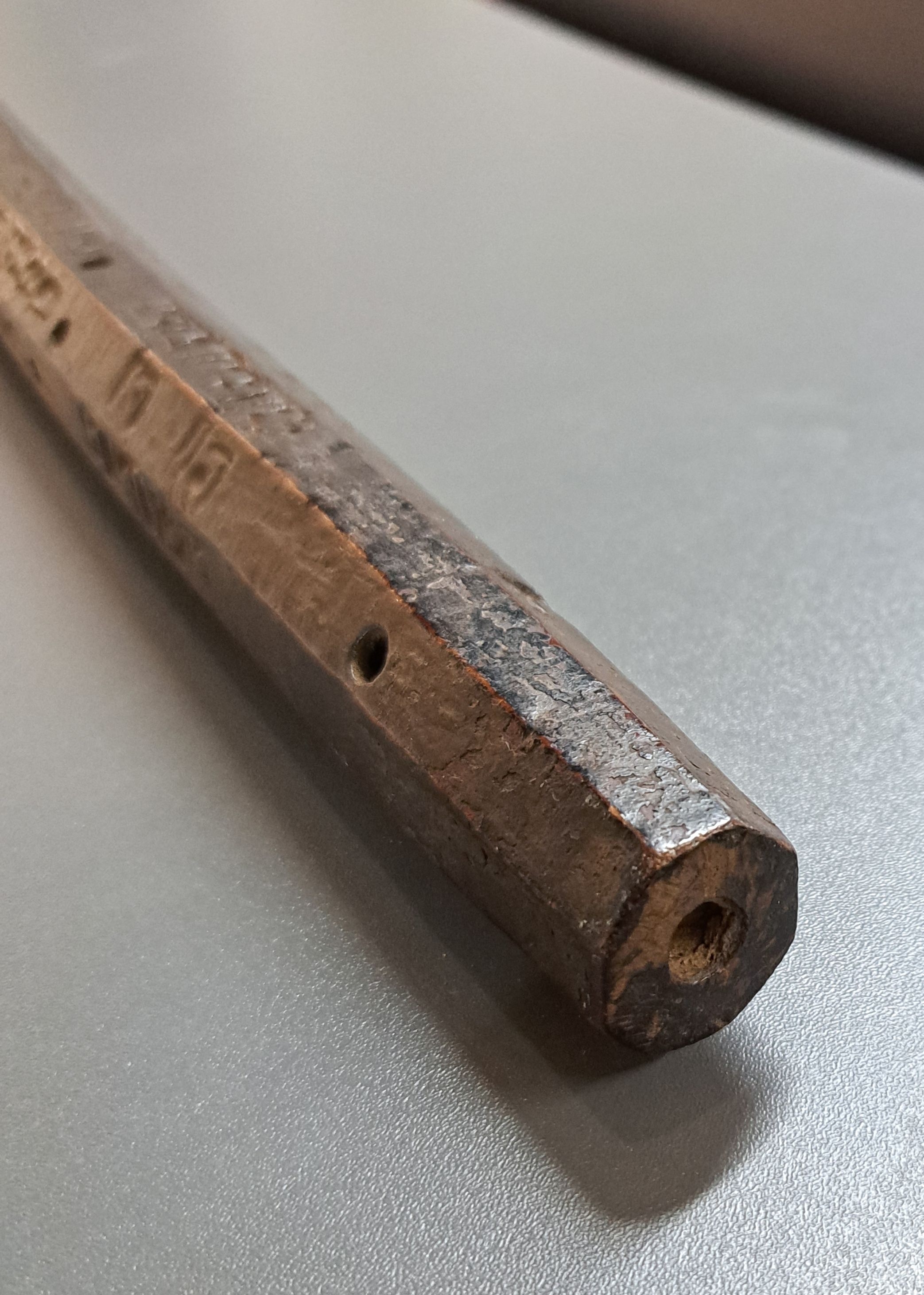 Detail b: Tibetanischer Schäferstock als Sonnenuhr, aus einem Stück Holz gehauen, dunkel, achtkantig, jede Seite verschiedene Buchstaben u. Löcher, die, ...