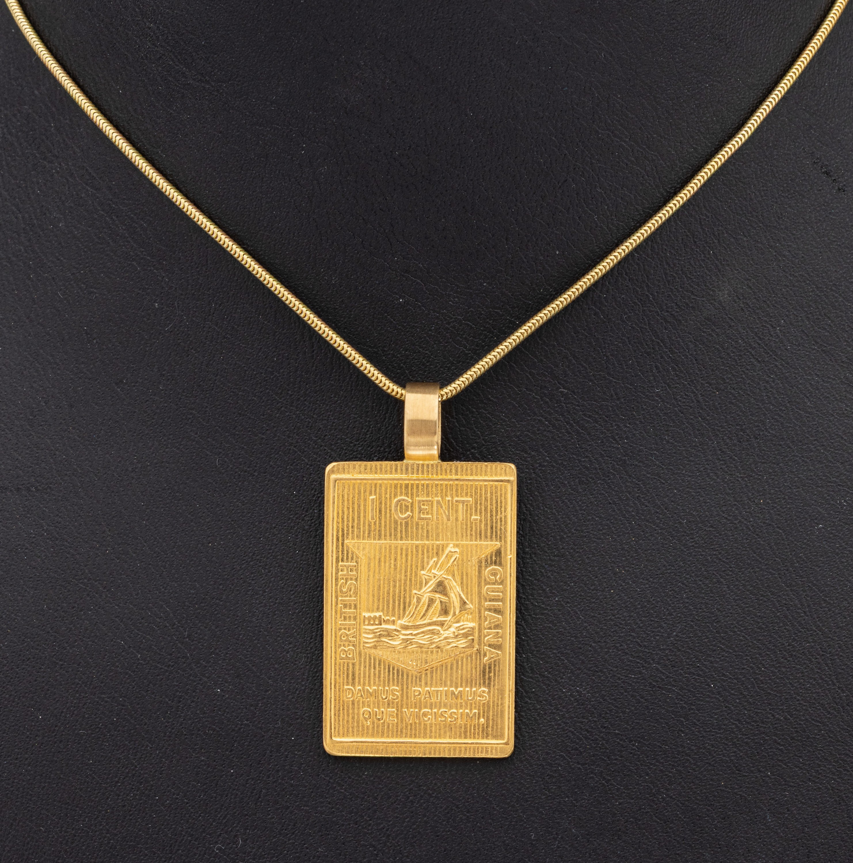 21.6 kt Gold Anhänger, GG 900/000, Darstellung: "Die älteste Briefmarke von British Guiana 1852, one Cent schwarz-rot, Auflage 15000, ...