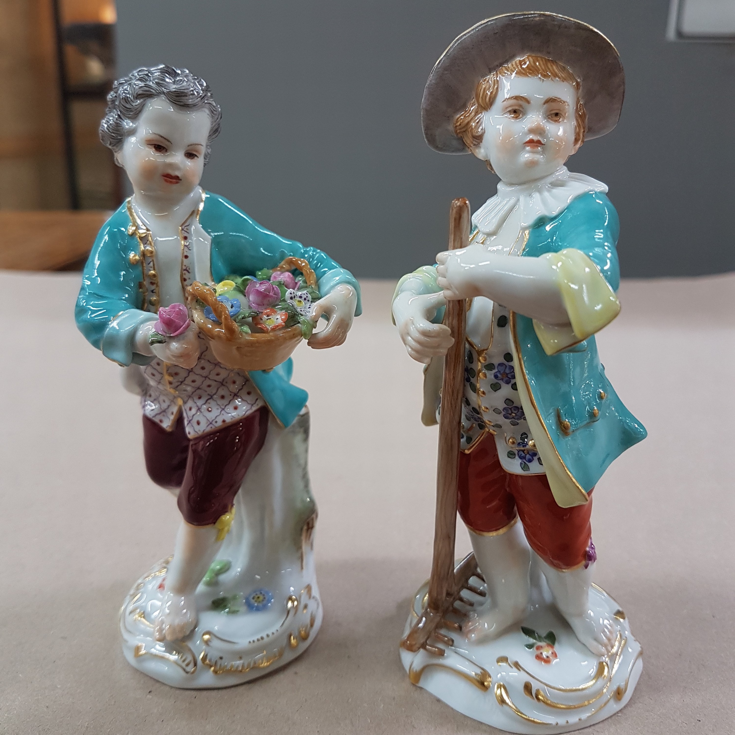 Detail b: 2 Porzellanfiguren, Meissen, 20. Jh., 1. Wahl, Gärtnerkinder mit Rechen bzw. Blumenkorb, bunt bemalt, Goldstaffage, H. ca. 13 bzw. 13.5cm