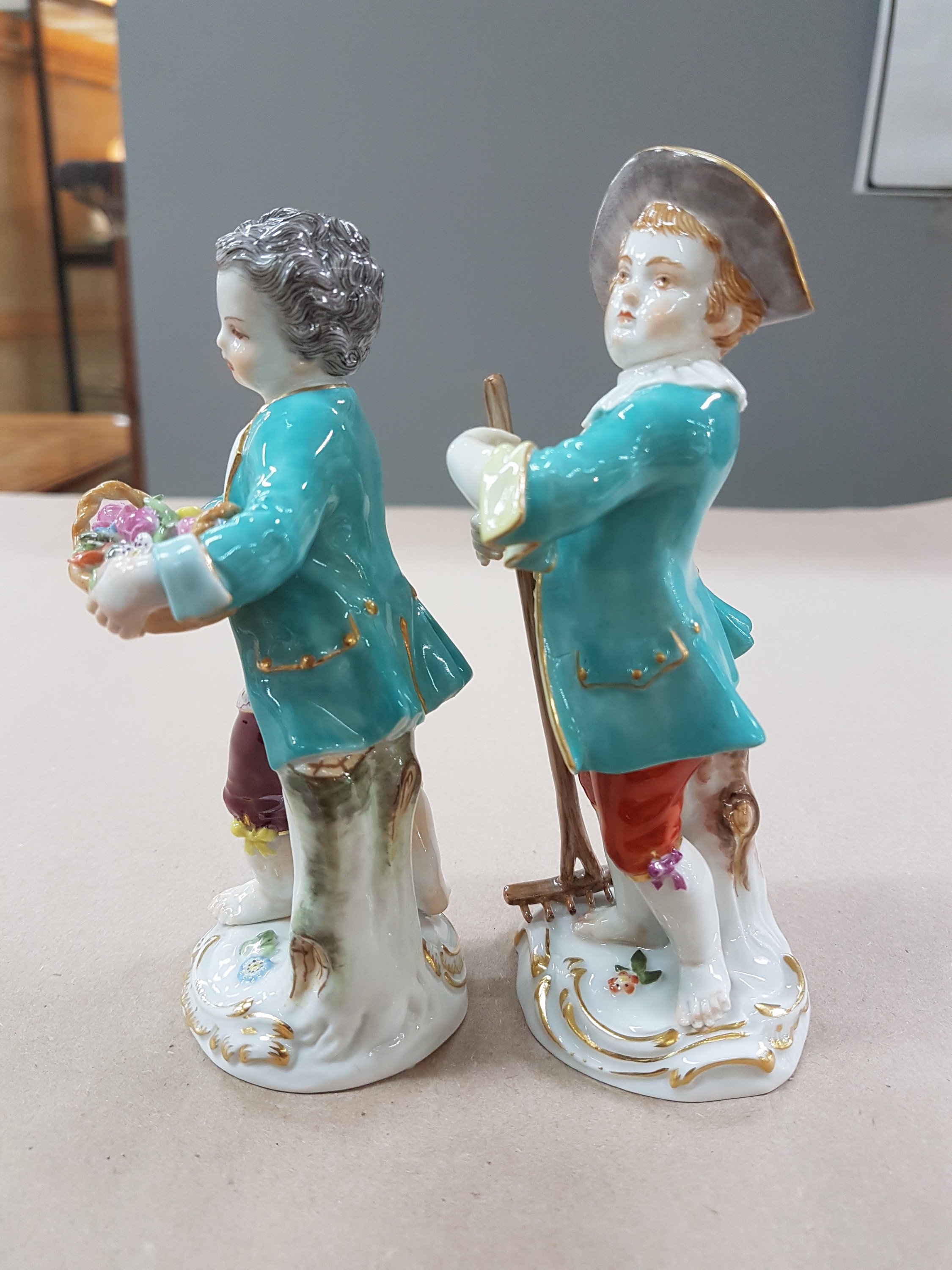 Detail e: 2 Porzellanfiguren, Meissen, 20. Jh., 1. Wahl, Gärtnerkinder mit Rechen bzw. Blumenkorb, bunt bemalt, Goldstaffage, H. ca. 13 bzw. 13.5cm