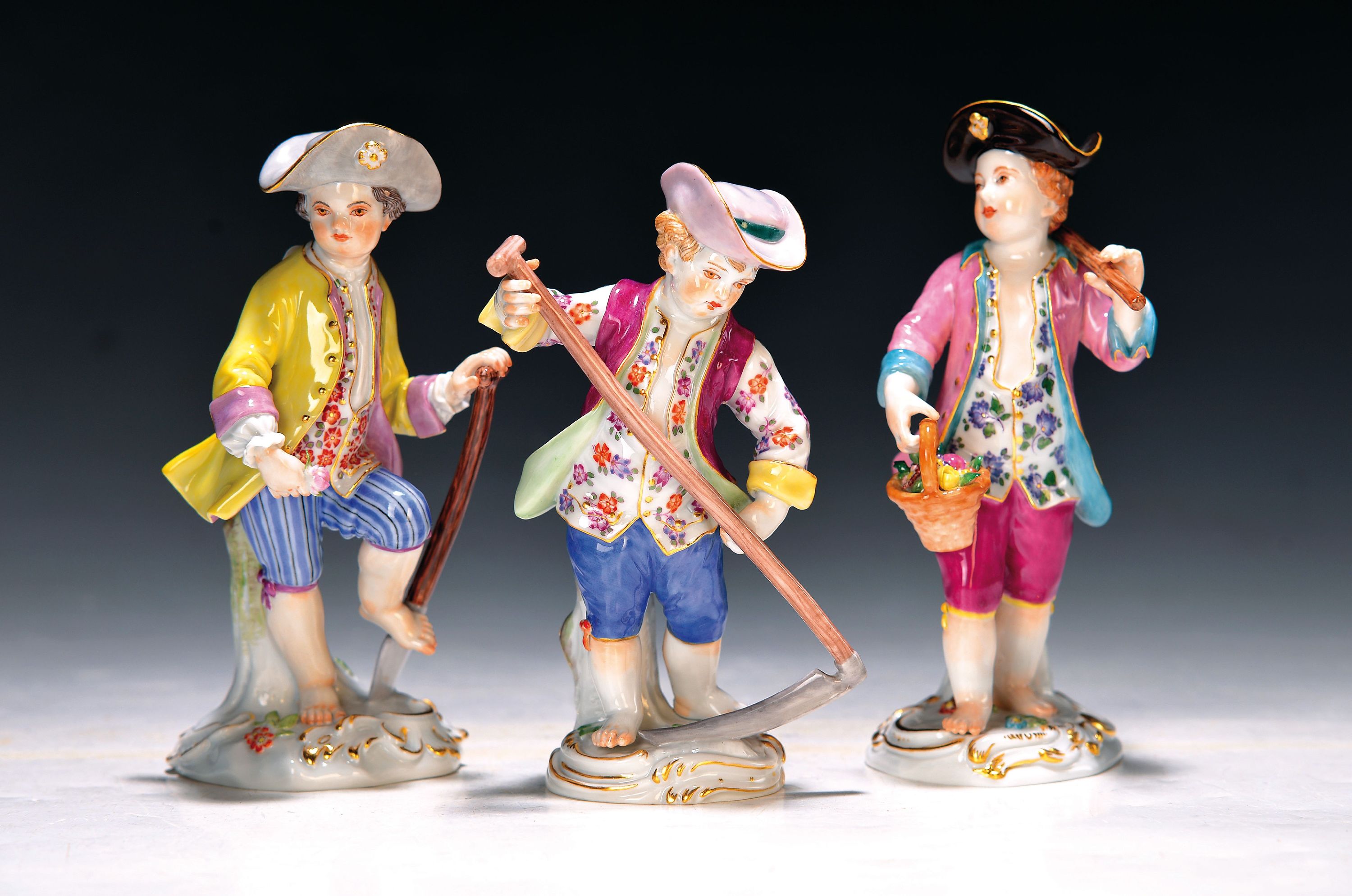 3 Porzellanfiguren, Meissen, 20. Jh., 1. Wahl, Gärtnerkinder mit Sense, Spaten und Harke, bunt bemalt, Goldstaffage, H. ca. 13-14cm