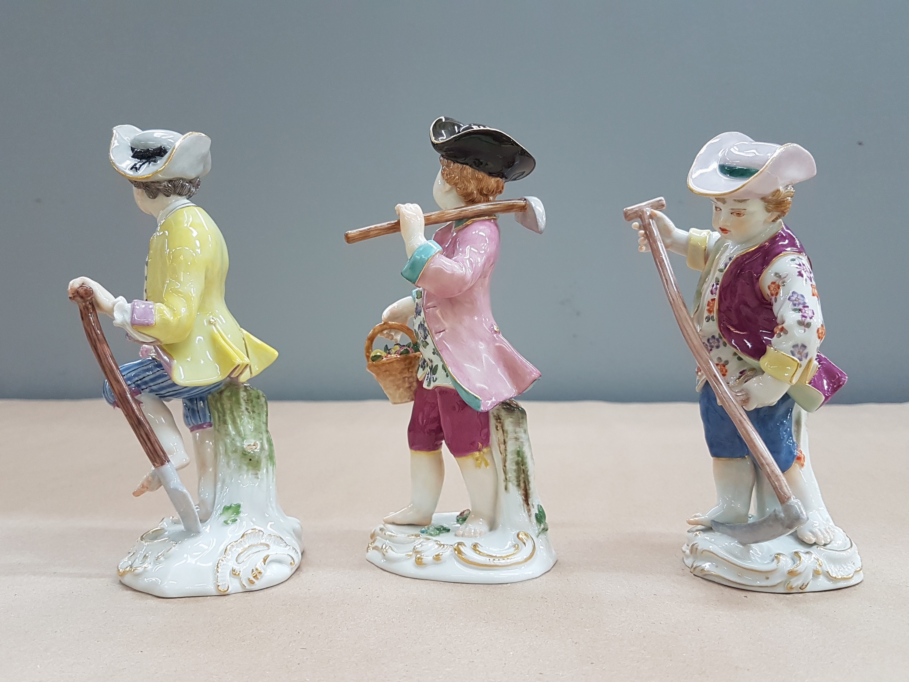 Detail e: 3 Porzellanfiguren, Meissen, 20. Jh., 1. Wahl, Gärtnerkinder mit Sense, Spaten und Harke, bunt bemalt, Goldstaffage, H. ca. 13-14cm