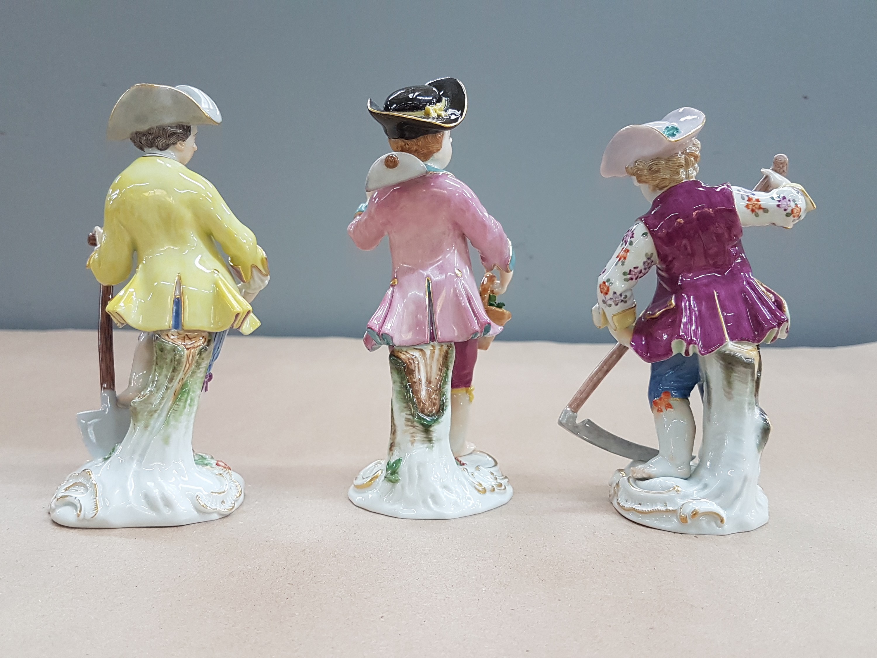 Detail f: 3 Porzellanfiguren, Meissen, 20. Jh., 1. Wahl, Gärtnerkinder mit Sense, Spaten und Harke, bunt bemalt, Goldstaffage, H. ca. 13-14cm