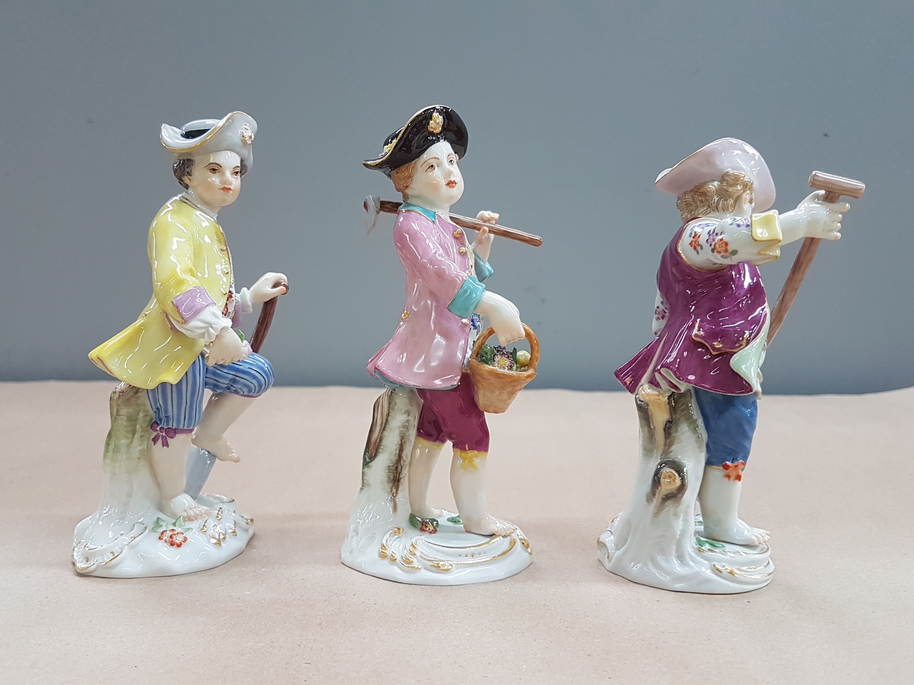Detail g: 3 Porzellanfiguren, Meissen, 20. Jh., 1. Wahl, Gärtnerkinder mit Sense, Spaten und Harke, bunt bemalt, Goldstaffage, H. ca. 13-14cm