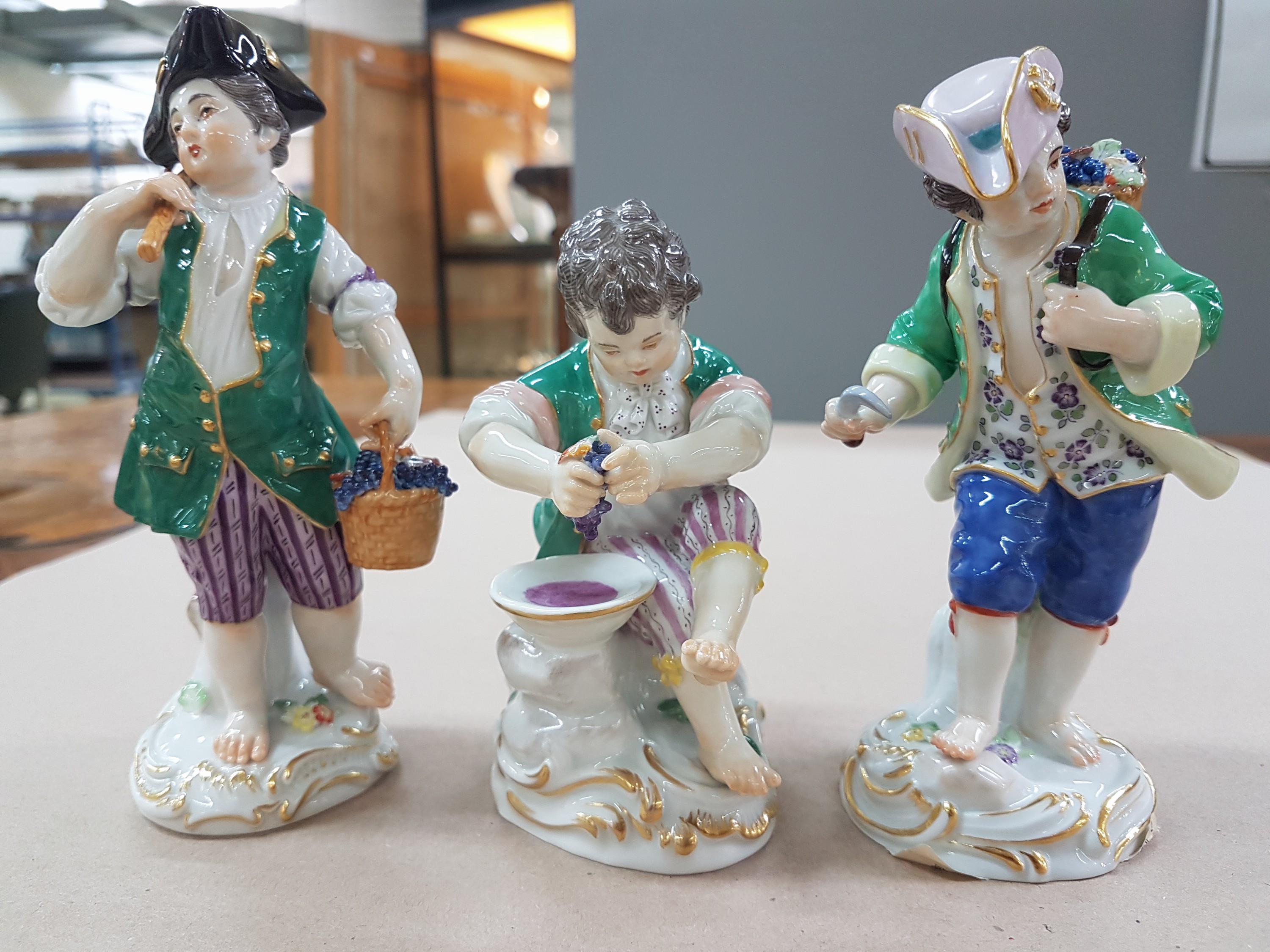 Detail a: 3 Porzellanfiguren, Meissen, 20. Jh., 1. Wahl, 3 Winzerknaben mit roten Trauben in Kiepe, Korb und beim Auspressen, H. ca. 11-14 cm
