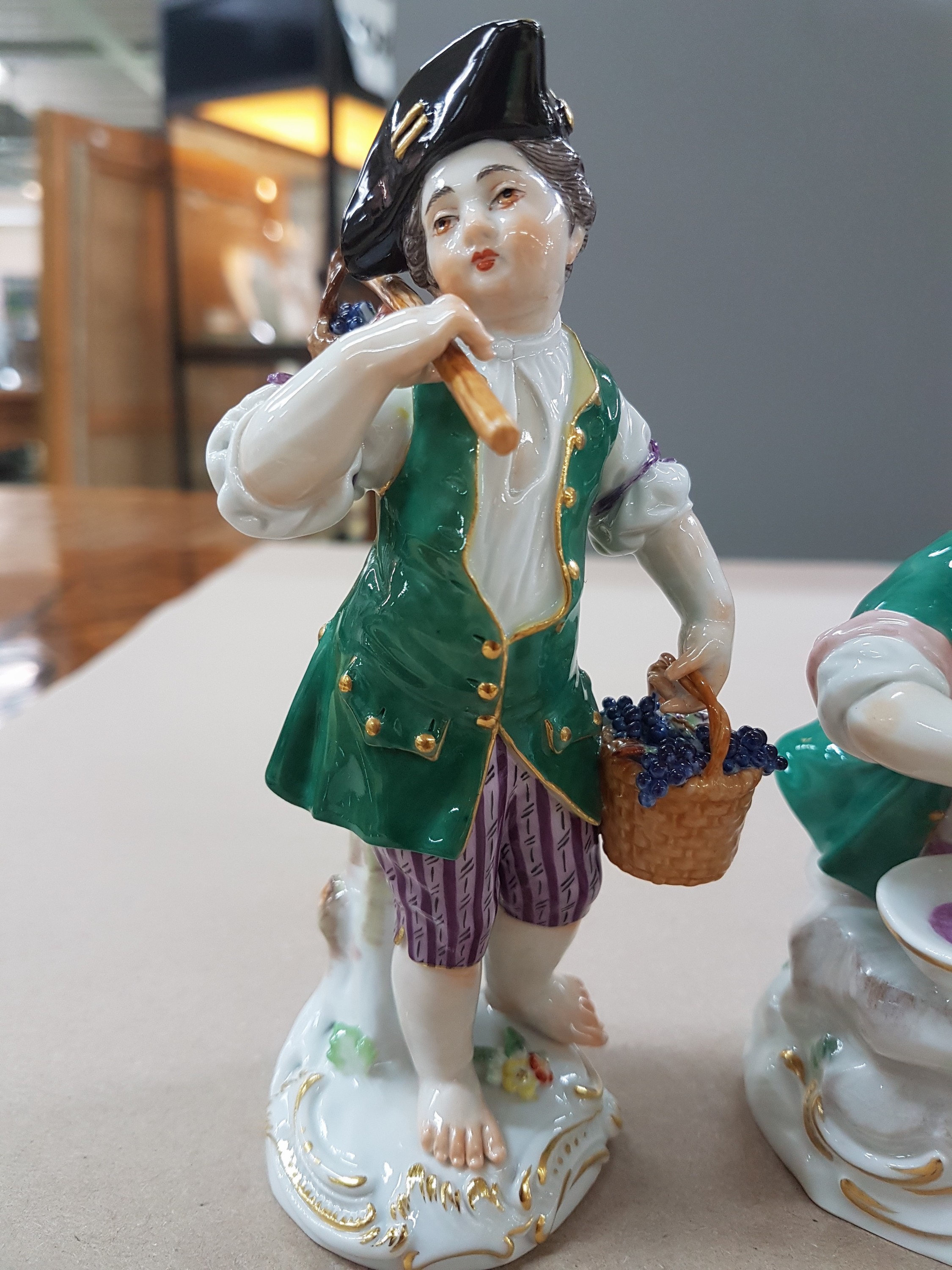Detail b: 3 Porzellanfiguren, Meissen, 20. Jh., 1. Wahl, 3 Winzerknaben mit roten Trauben in Kiepe, Korb und beim Auspressen, H. ca. 11-14 cm