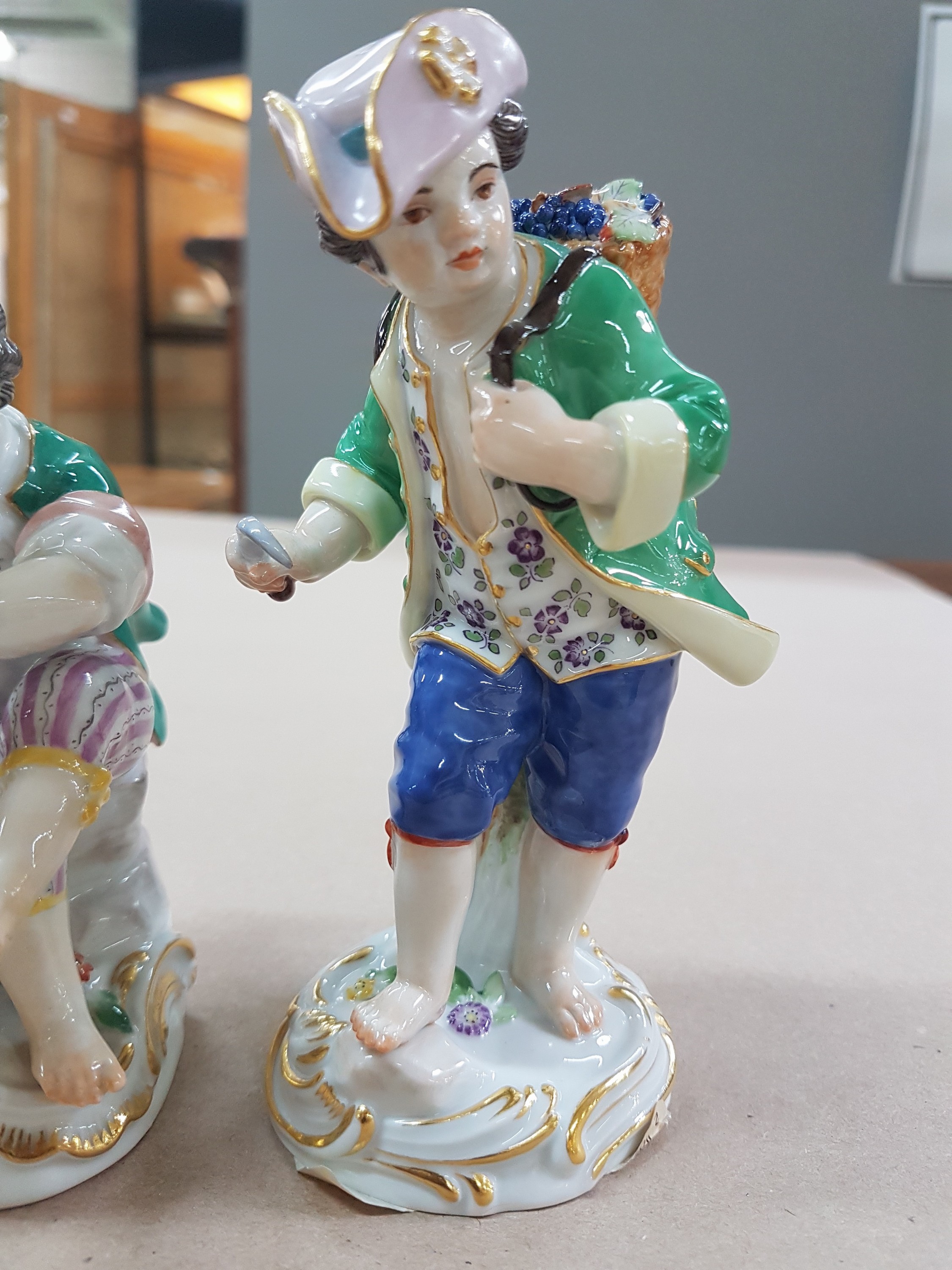 Detail d: 3 Porzellanfiguren, Meissen, 20. Jh., 1. Wahl, 3 Winzerknaben mit roten Trauben in Kiepe, Korb und beim Auspressen, H. ca. 11-14 cm