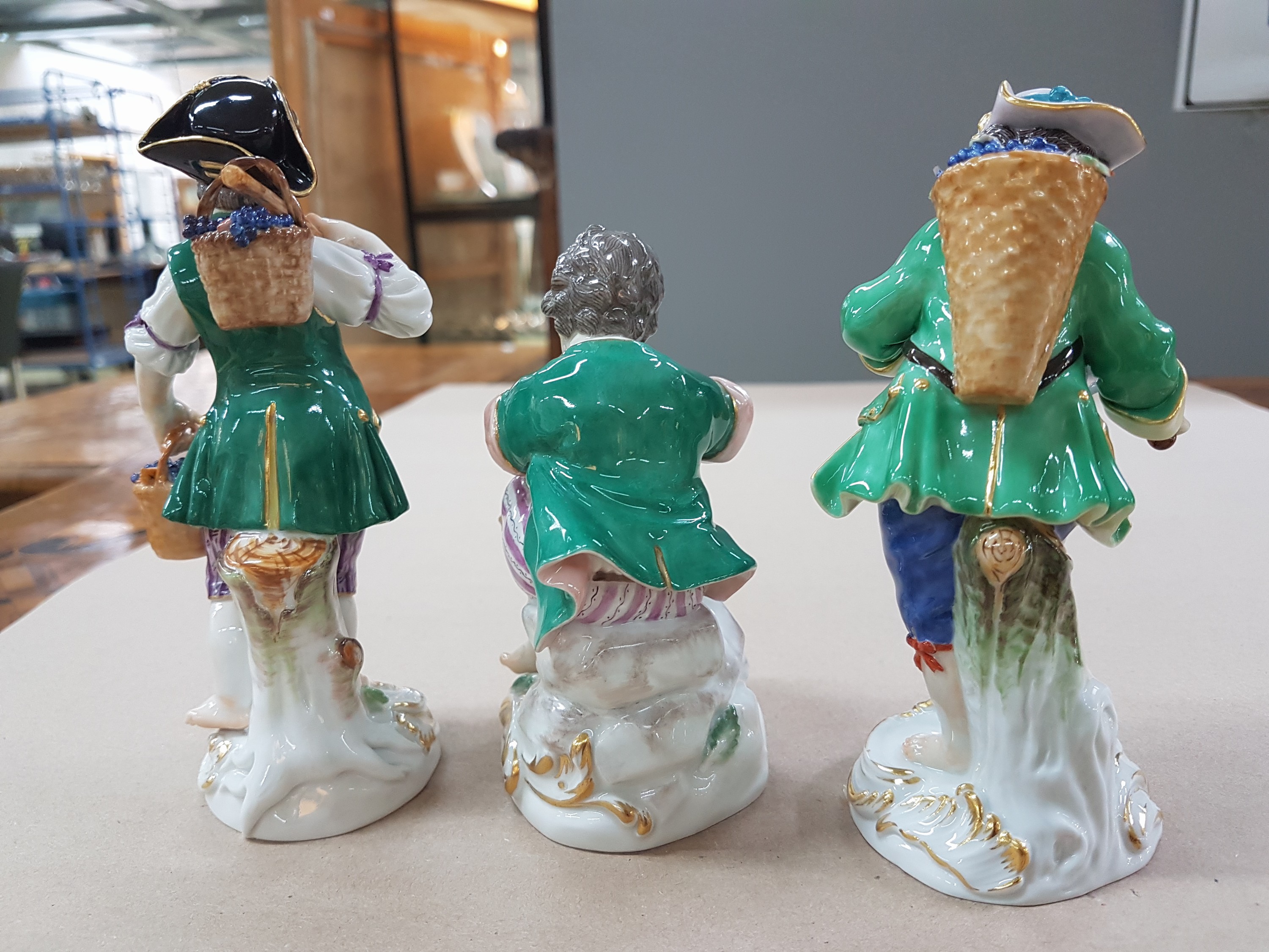 Detail f: 3 Porzellanfiguren, Meissen, 20. Jh., 1. Wahl, 3 Winzerknaben mit roten Trauben in Kiepe, Korb und beim Auspressen, H. ca. 11-14 cm
