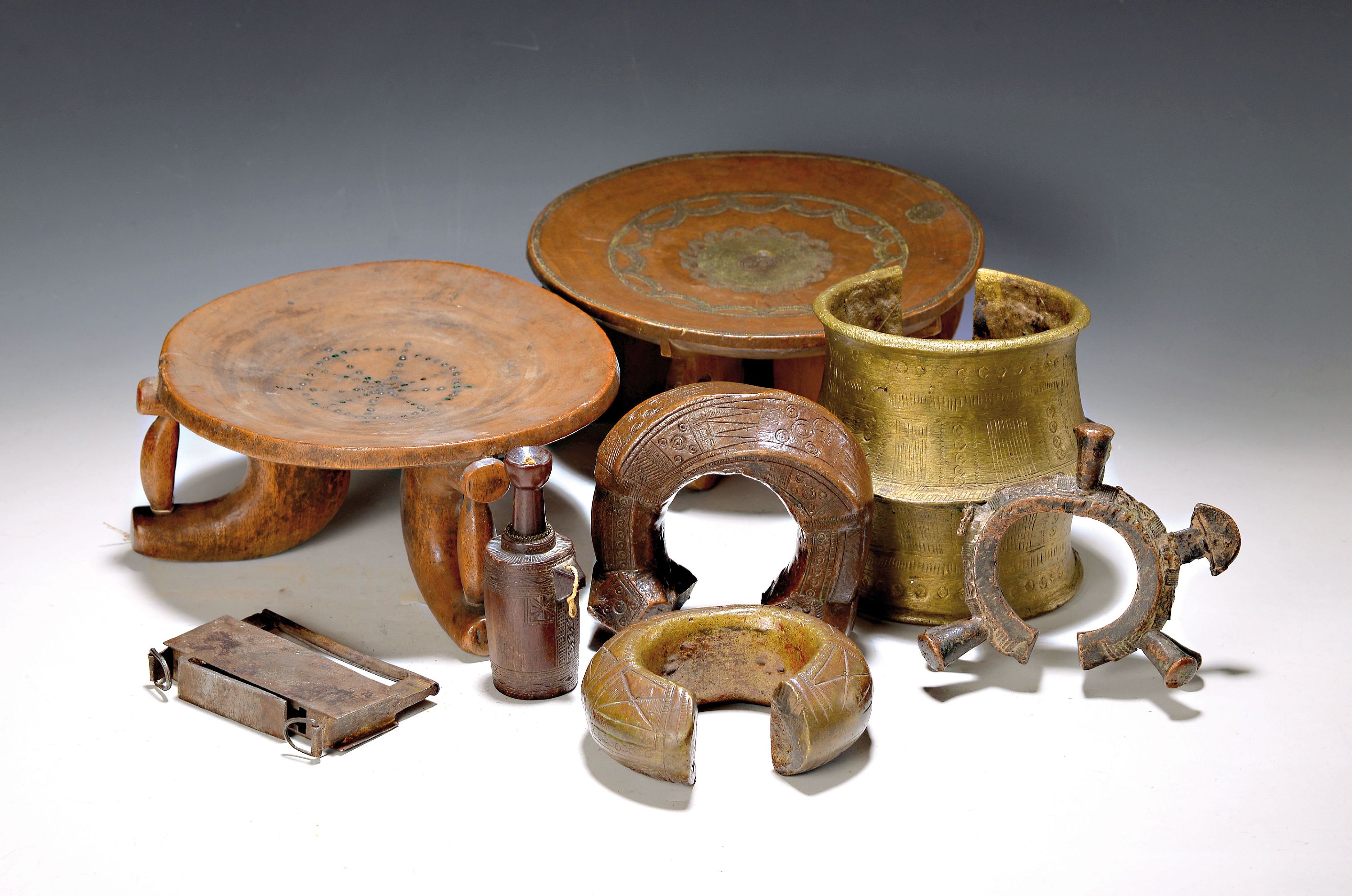 Vier Manilen, und zwei Fußschalen und ein Flakon, Westafrika, Anfang 20. Jh., Manilen aus Bronze und Messing, 12-14 cm, Flakon, geschnitzt, H. ca. ...