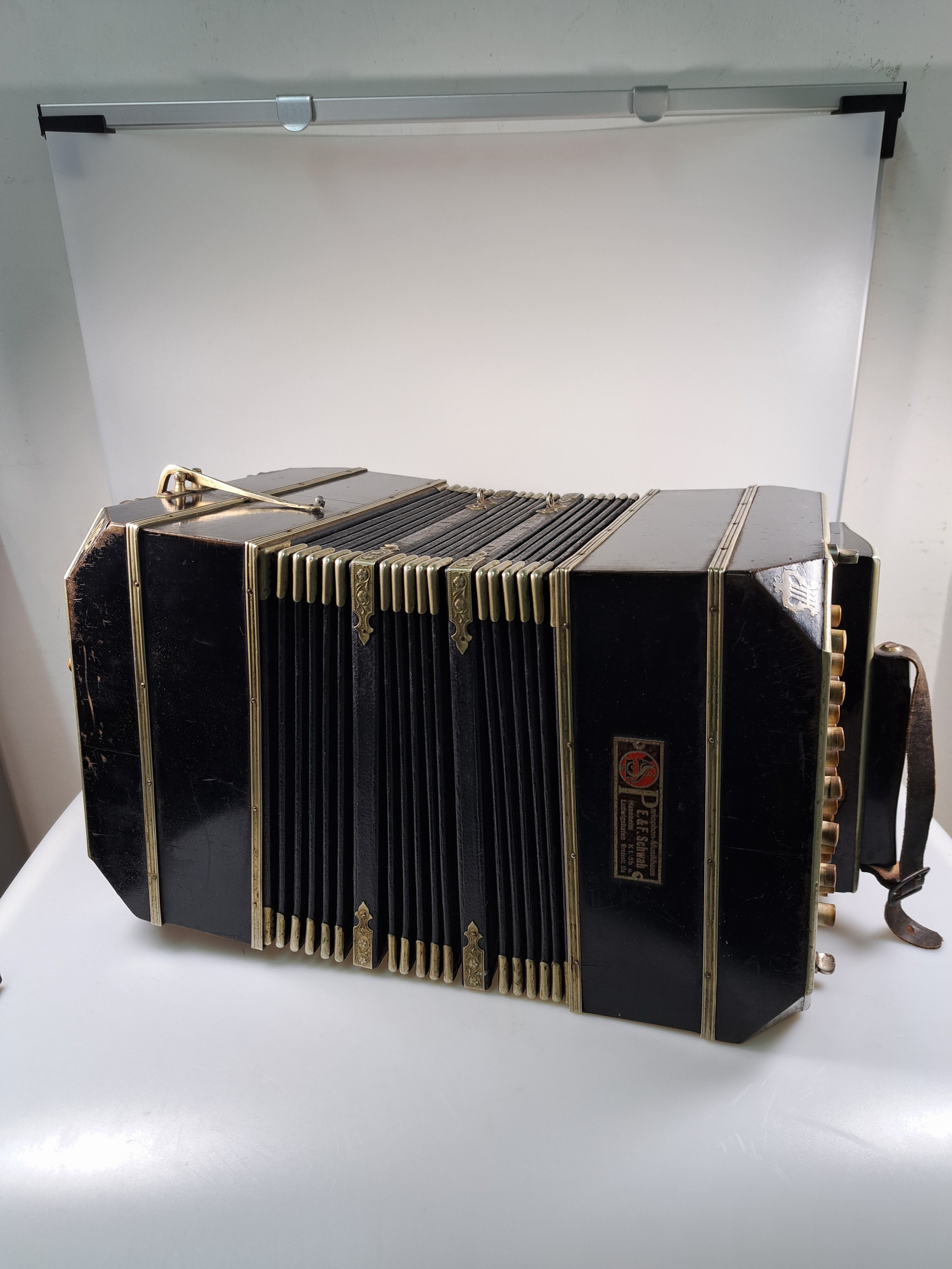 Detail b: Bandoneon, wohl Alfred Arnold, 1.H. 20. Jh., Holzgehäuse mit Lyraeinlagen in Metall an den abgeschrägten Ecken, Laubsägearbeiten seitliche mit ...