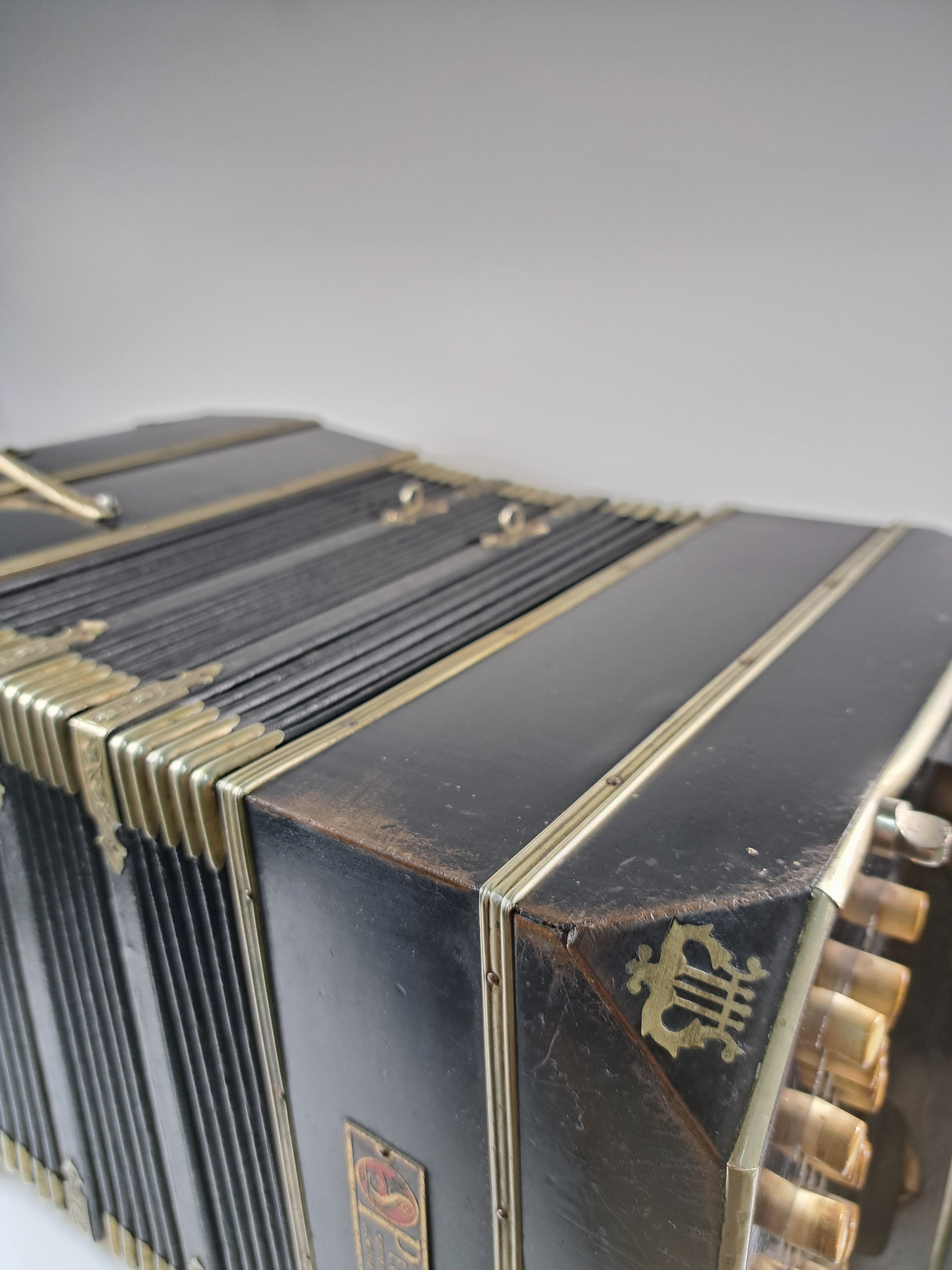 Detail f: Bandoneon, wohl Alfred Arnold, 1.H. 20. Jh., Holzgehäuse mit Lyraeinlagen in Metall an den abgeschrägten Ecken, Laubsägearbeiten seitliche mit ...
