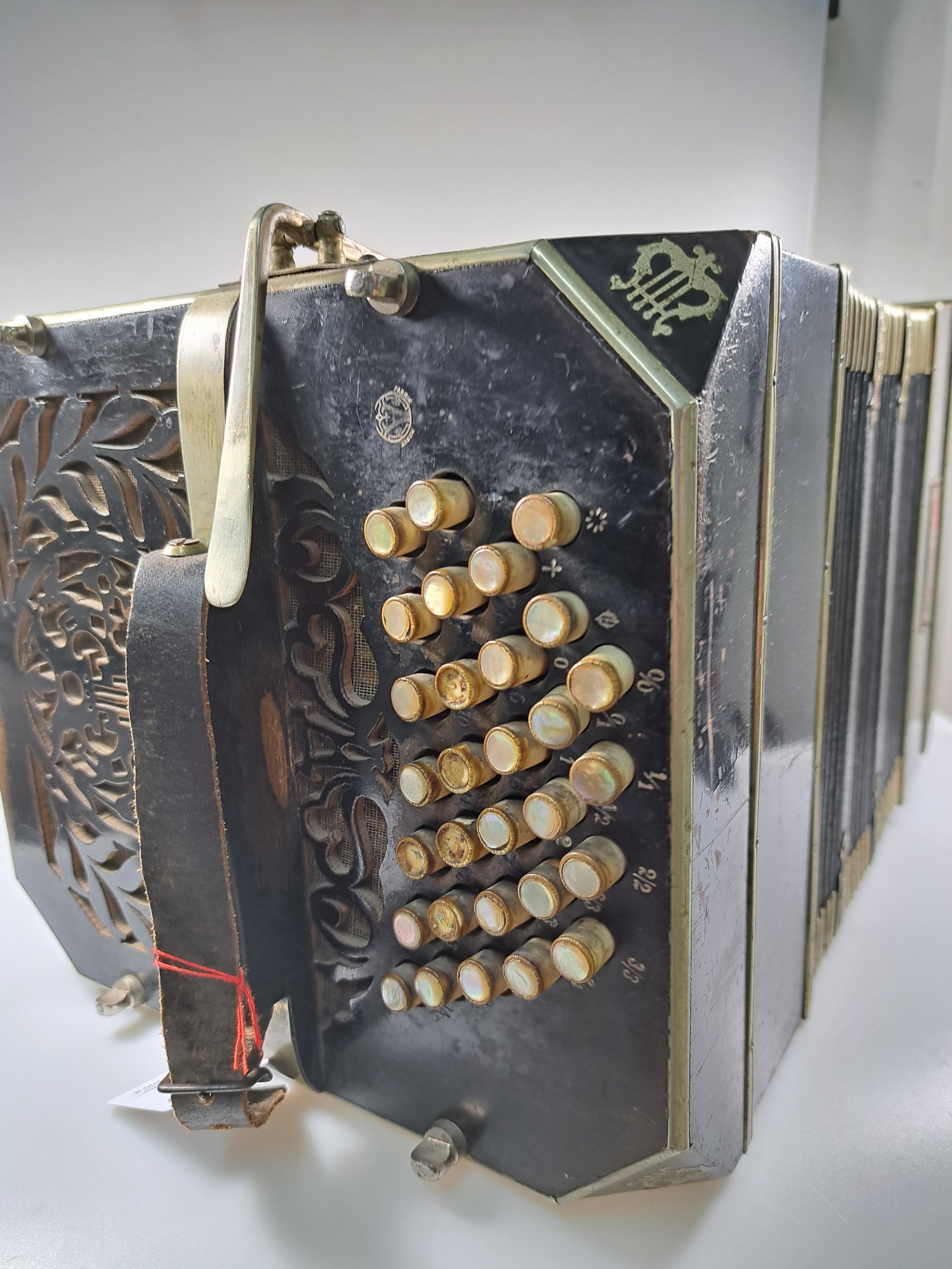 Detail h: Bandoneon, wohl Alfred Arnold, 1.H. 20. Jh., Holzgehäuse mit Lyraeinlagen in Metall an den abgeschrägten Ecken, Laubsägearbeiten seitliche mit ...